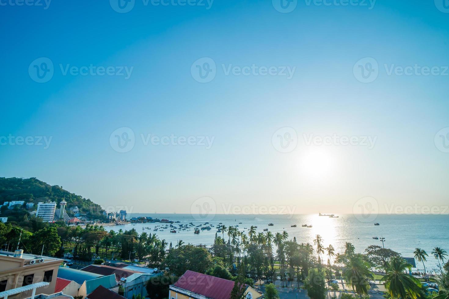 Vung Tau city aerial view with beautiful sunset and so many boats. Panoramic coastal Vung Tau view from above, with waves, coastline, streets, coconut trees and Tao Phung mountain in Vietnam. photo