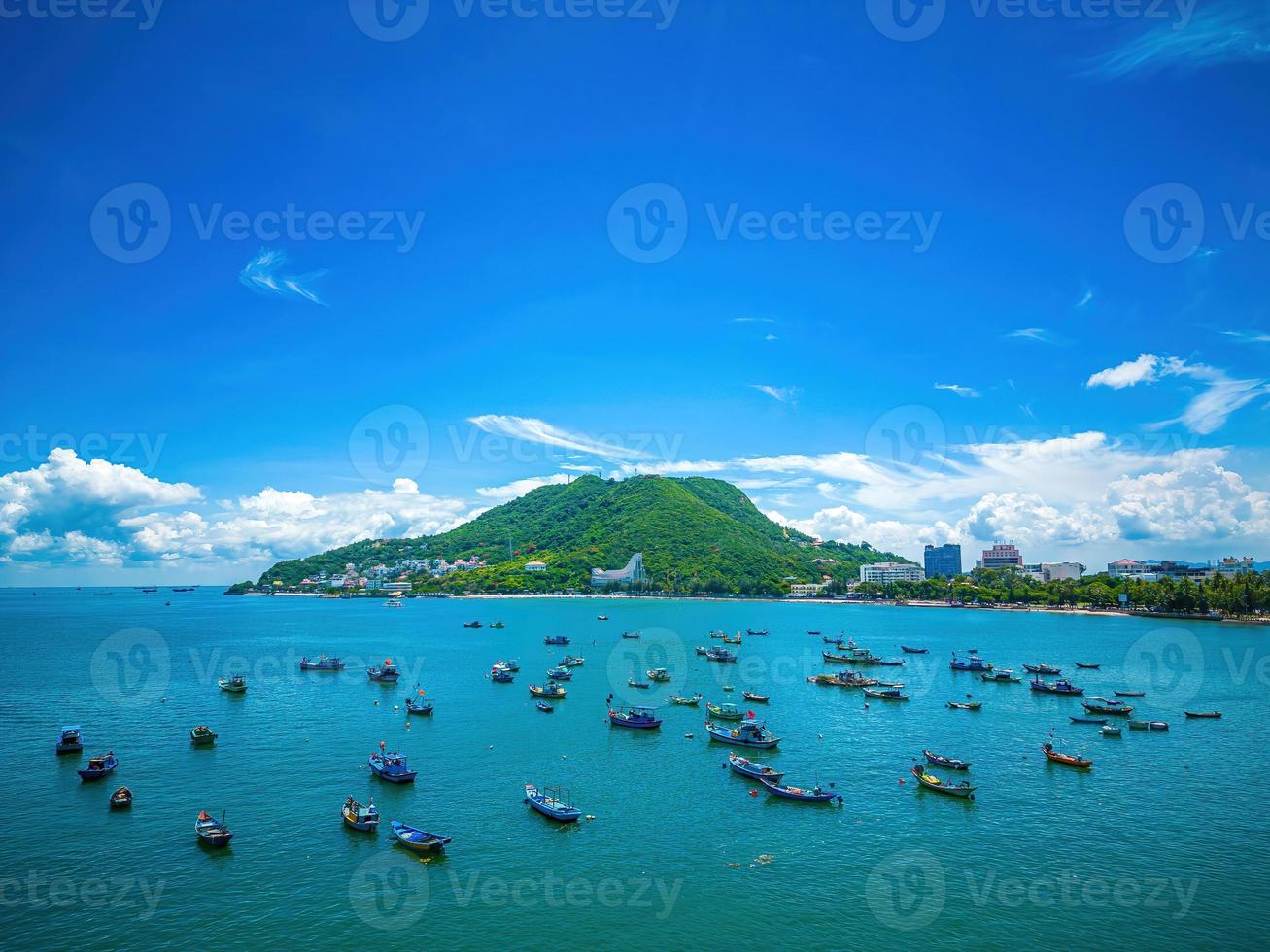 Vung Tau city aerial view with beautiful sunset and so many boats. Panoramic coastal Vung Tau view from above, with waves, coastline, streets, coconut trees and Tao Phung mountain in Vietnam. photo