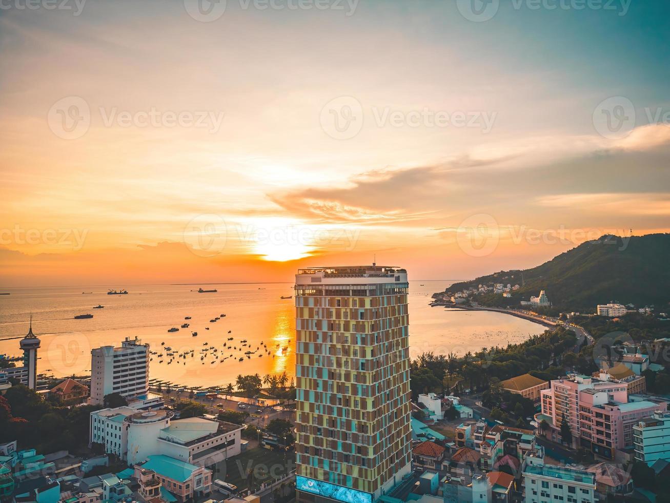 Vung Tau city aerial view with beautiful sunset and so many boats. Panoramic coastal Vung Tau view from above, with waves, coastline, streets, coconut trees and Tao Phung mountain in Vietnam. photo