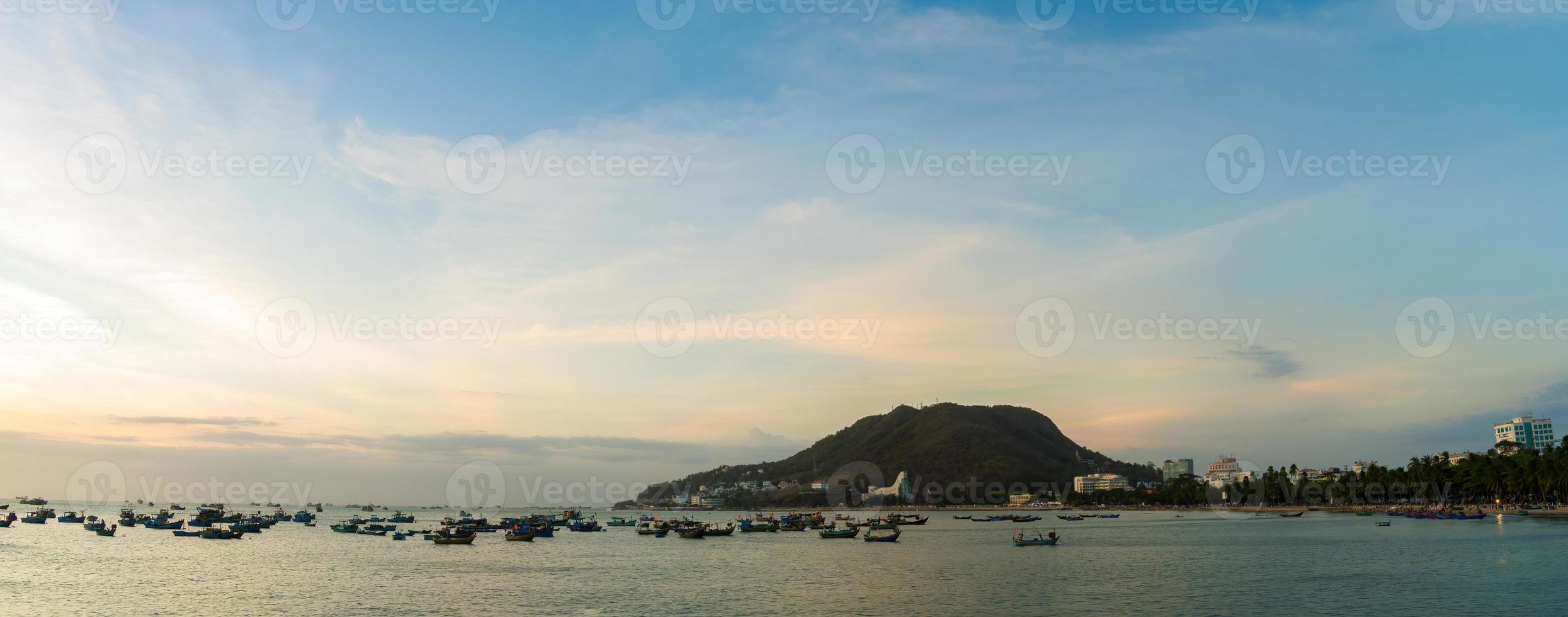 Vung Tau city aerial view with beautiful sunset and so many boats. Panoramic coastal Vung Tau view from above, with waves, coastline, streets, coconut trees and Tao Phung mountain in Vietnam. photo