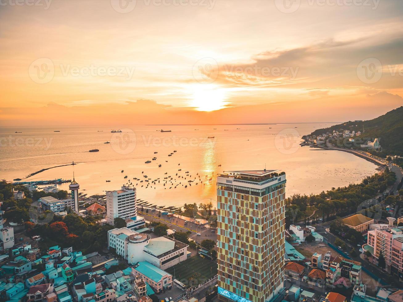 Vung Tau city aerial view with beautiful sunset and so many boats. Panoramic coastal Vung Tau view from above, with waves, coastline, streets, coconut trees and Tao Phung mountain in Vietnam. photo