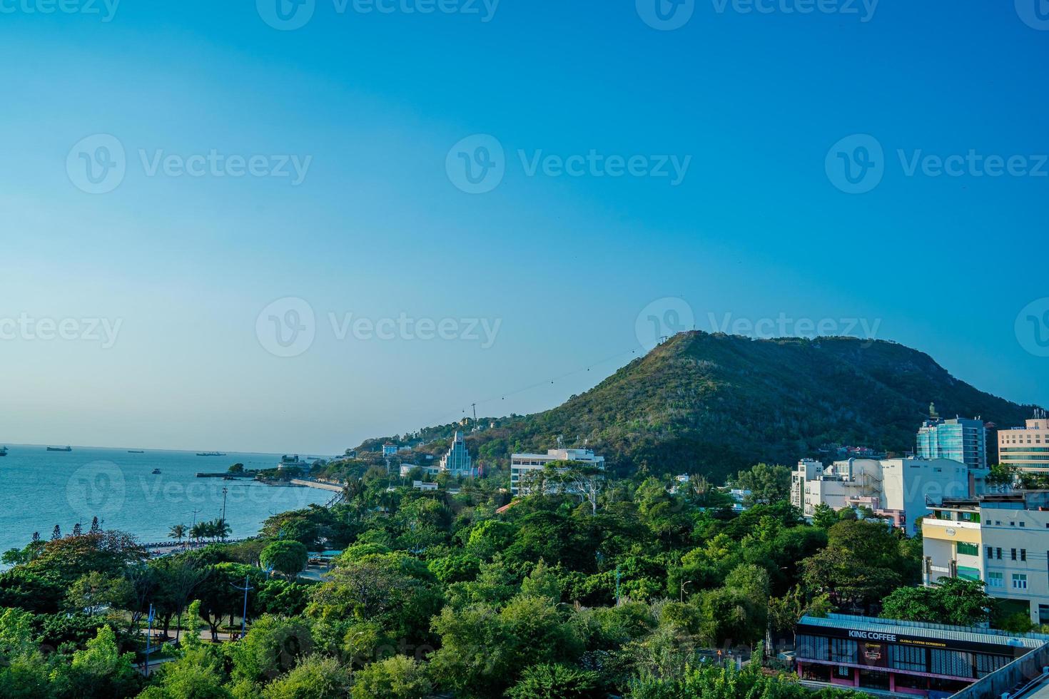 Vung Tau city aerial view with beautiful sunset and so many boats. Panoramic coastal Vung Tau view from above, with waves, coastline, streets, coconut trees and Tao Phung mountain in Vietnam. photo