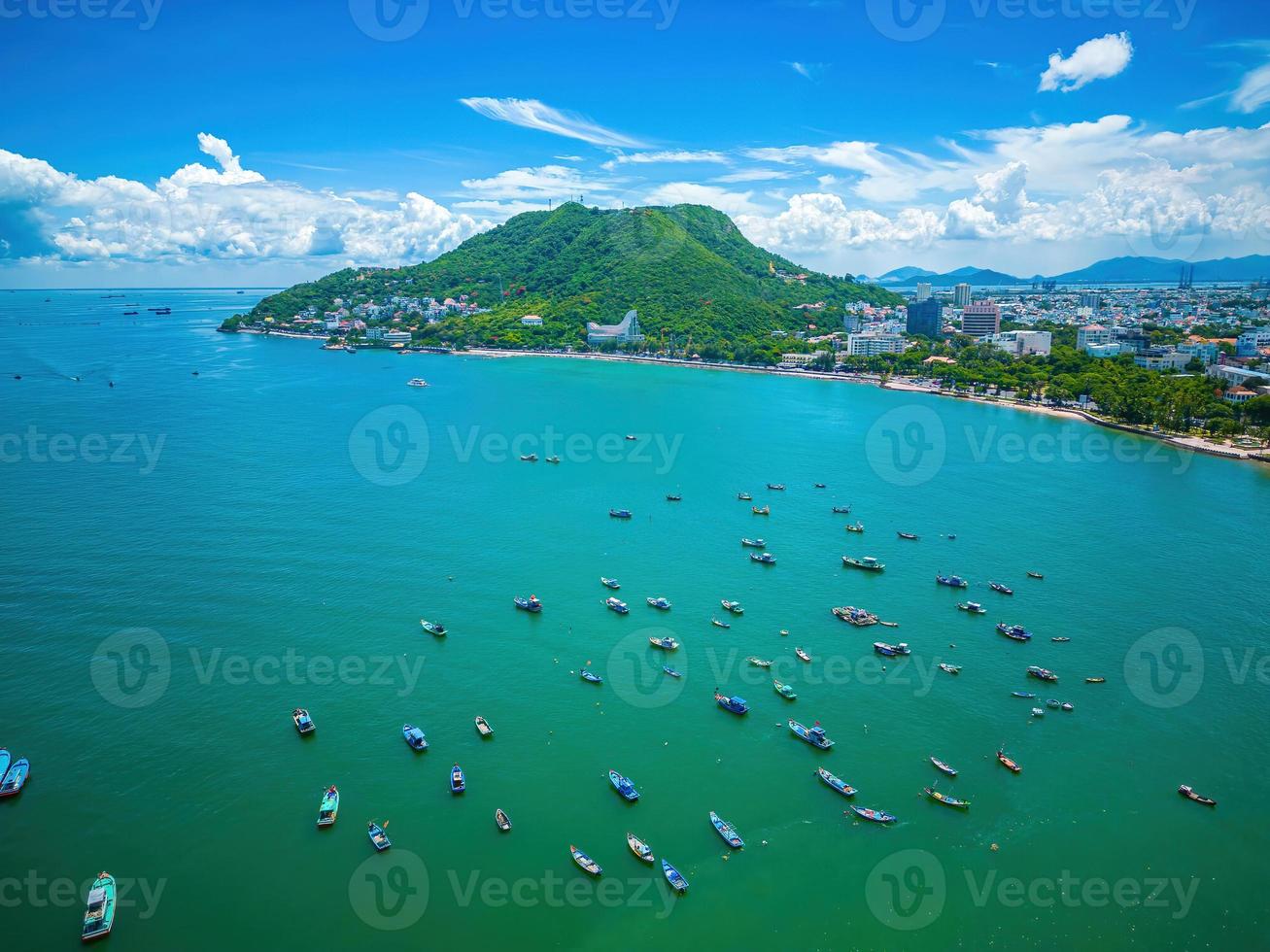 Vung Tau city aerial view with beautiful sunset and so many boats. Panoramic coastal Vung Tau view from above, with waves, coastline, streets, coconut trees and Tao Phung mountain in Vietnam. photo
