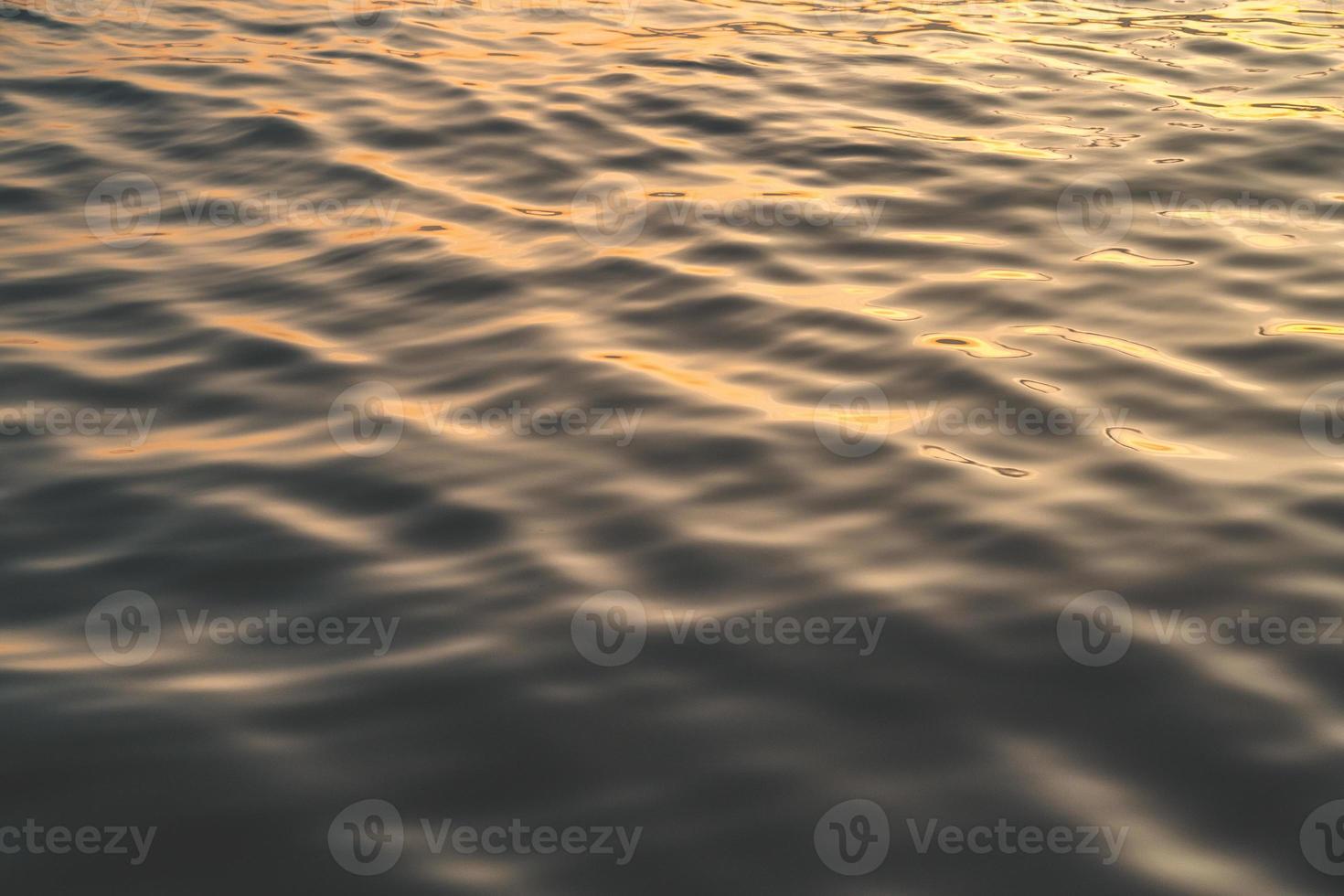 Sunset water reflect ripples at sun light. Abstract golden reflection on water sunset photo