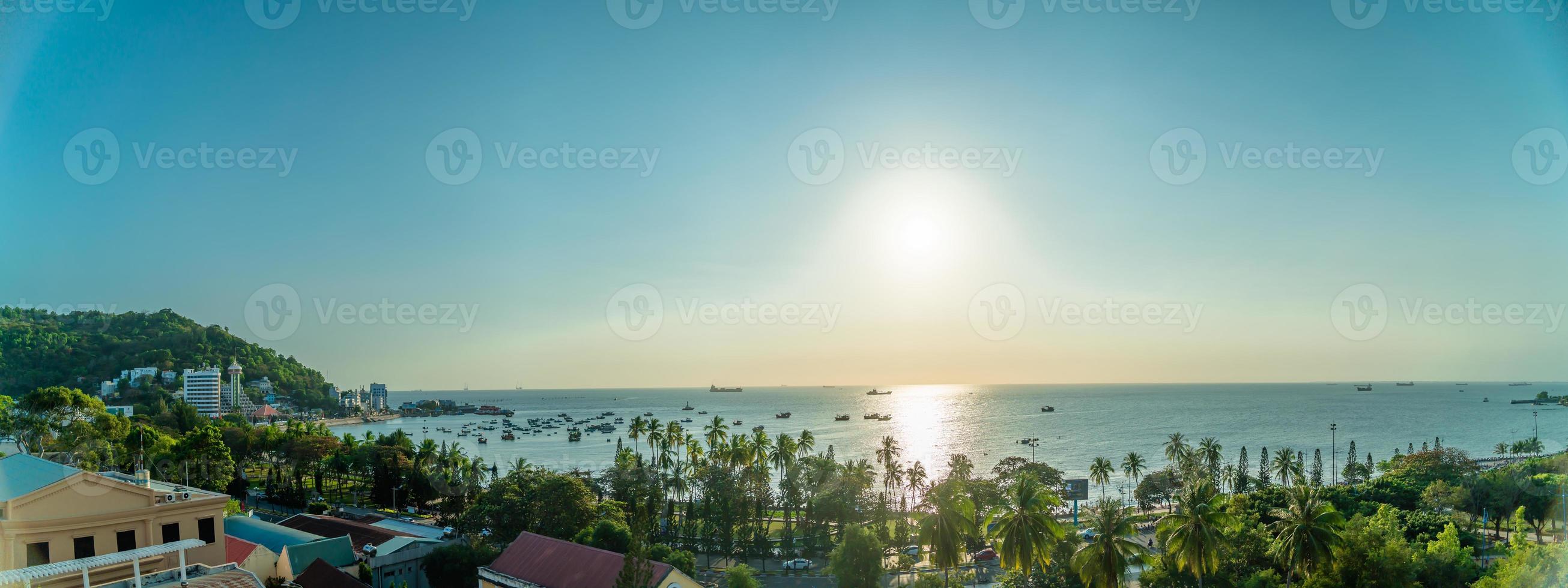 Vung Tau city aerial view with beautiful sunset and so many boats. Panoramic coastal Vung Tau view from above, with waves, coastline, streets, coconut trees and Tao Phung mountain in Vietnam. photo
