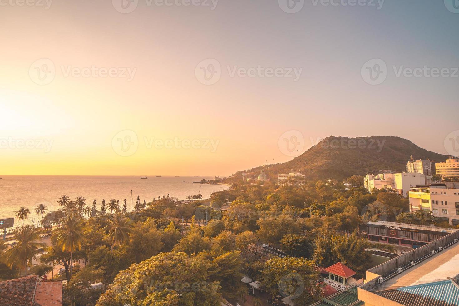 vista aérea de la ciudad de vung tau con hermosa puesta de sol y tantos barcos. vista panorámica costera de vung tau desde arriba, con olas, costa, calles, cocoteros y montaña tao phung en vietnam. foto