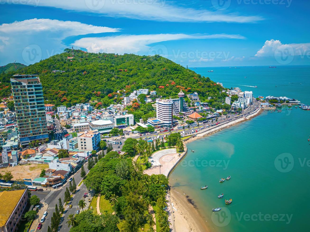 Vung Tau city aerial view with beautiful sunset and so many boats. Panoramic coastal Vung Tau view from above, with waves, coastline, streets, coconut trees and Tao Phung mountain in Vietnam. photo