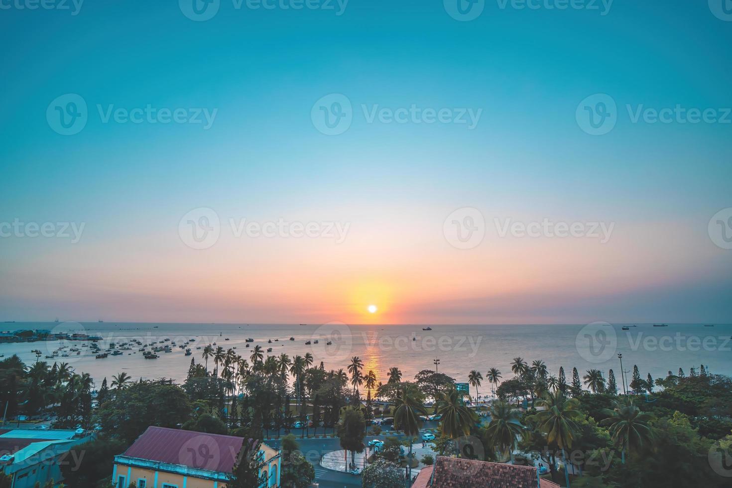 Vung Tau city aerial view with beautiful sunset and so many boats. Panoramic coastal Vung Tau view from above, with waves, coastline, streets, coconut trees and Tao Phung mountain in Vietnam. photo