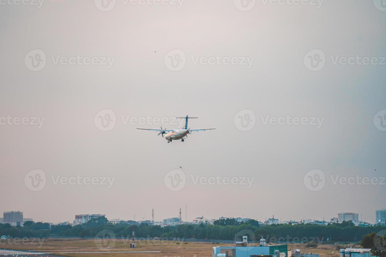 ciudad de ho chi minh, vietnam - 12 de febrero de 2022, un avión vuela sobre áreas urbanas preparando el aterrizaje en el aeropuerto internacional de tan son nhat y despega en el aeropuerto de tsn foto