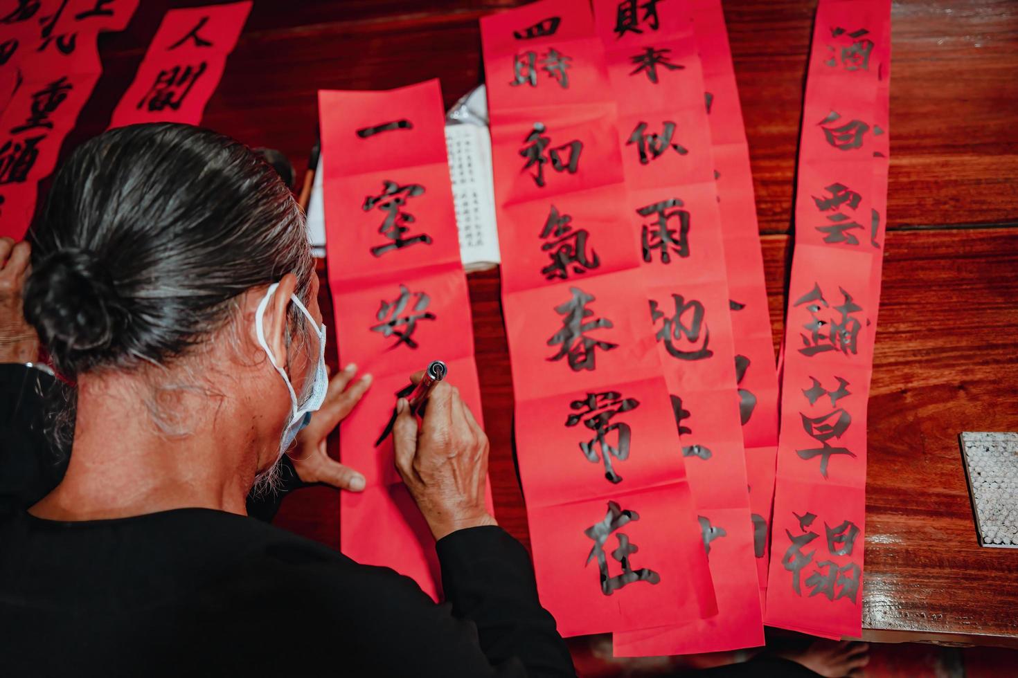 Vietnamese scholar writes calligraphy at Long Son. Calligraphy festival is a popular tradition during Tet holiday. Writing couplets for Spring Festival, new year. photo