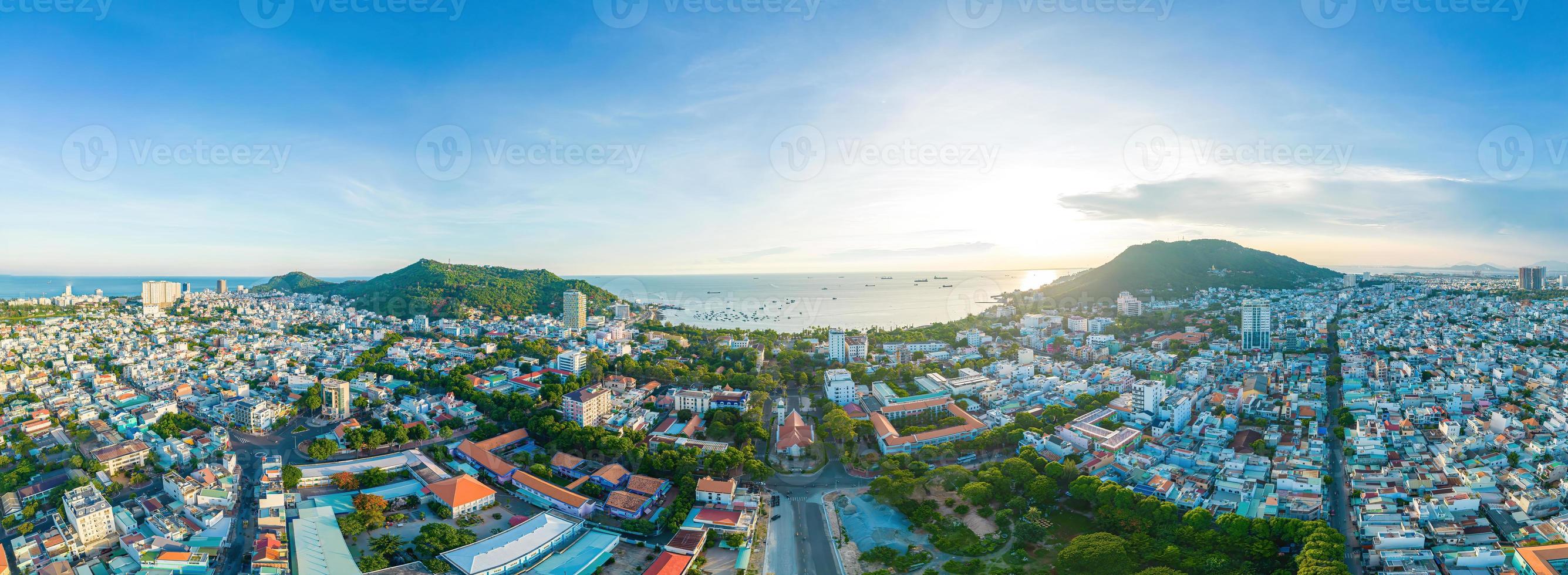 Vung Tau city aerial view with beautiful sunset and so many boats. Panoramic coastal Vung Tau view from above, with waves, coastline, streets, coconut trees and Tao Phung mountain in Vietnam. photo