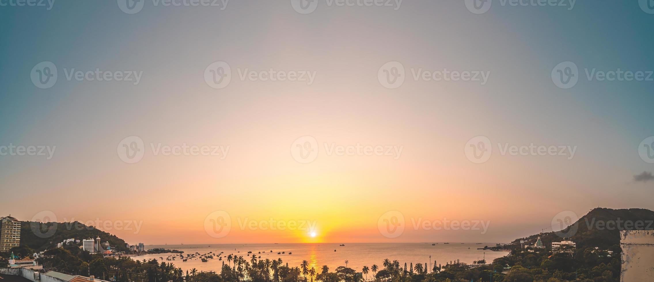 vista aérea de la ciudad de vung tau con hermosa puesta de sol y tantos barcos. vista panorámica costera de vung tau desde arriba, con olas, costa, calles, cocoteros y montaña tao phung en vietnam. foto