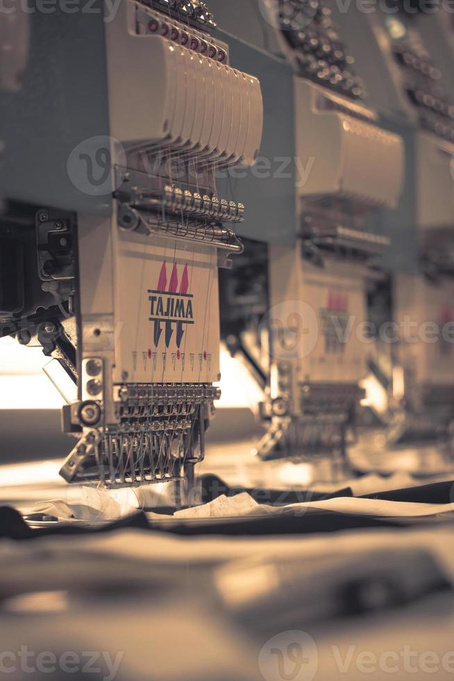 Modern and automatic high technology sewing machine for textile or clothing apparel making manufacturing process in industrial. Digital textile industry. Computerized embroidery. photo