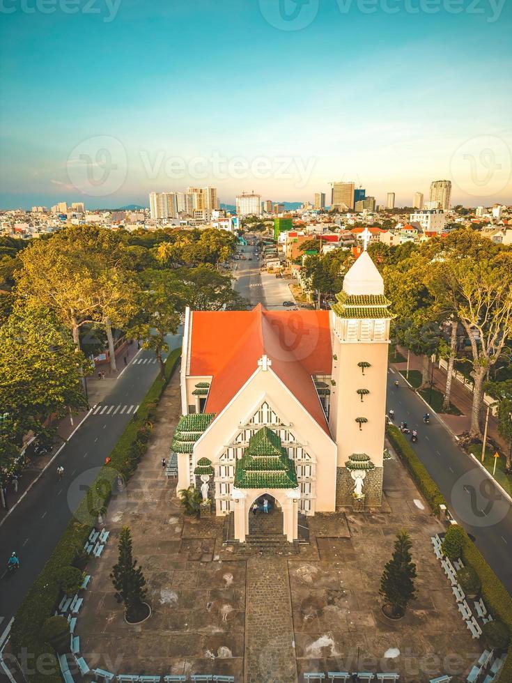 Top view of Beautiful old church of Vung Tau city with green tree. Catholic temple village of Vung Tau, Vietnam. Photo of spring landscape with sunset.