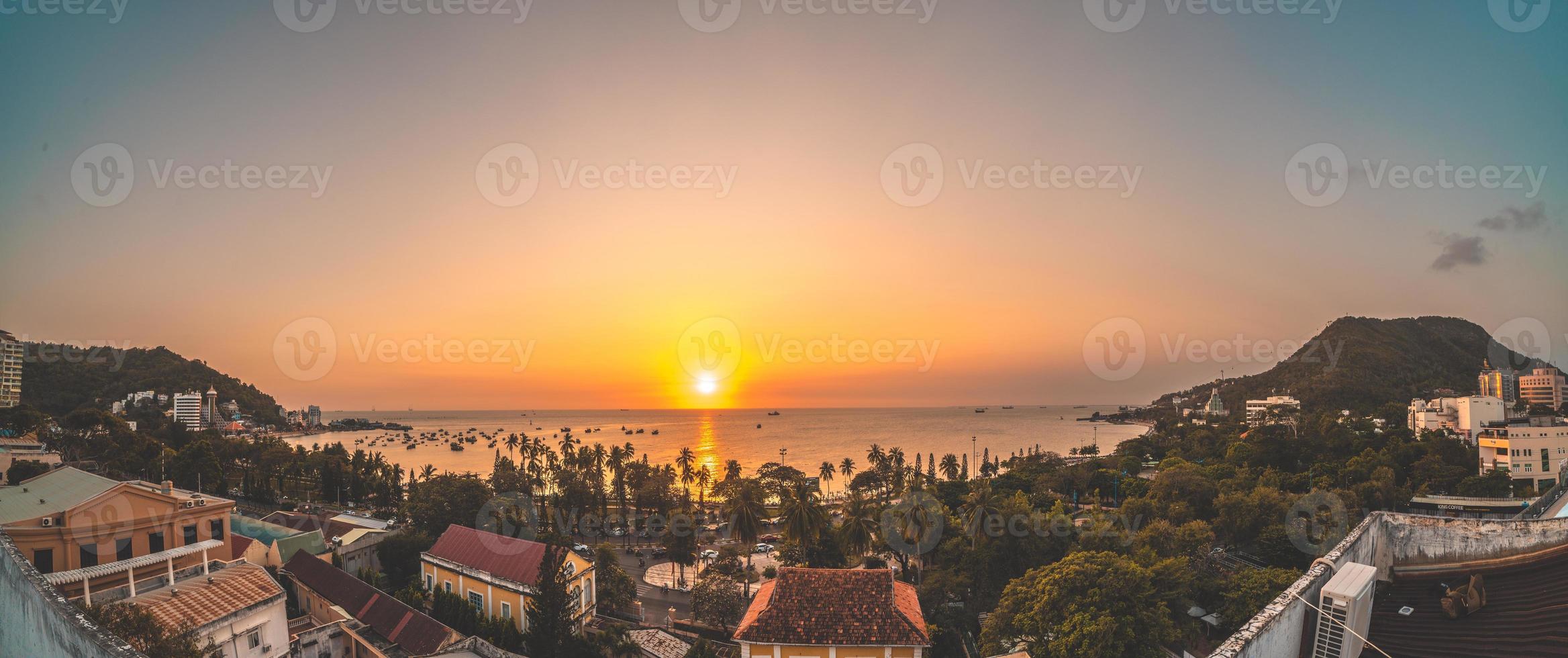 vista aérea de la ciudad de vung tau con hermosa puesta de sol y tantos barcos. vista panorámica costera de vung tau desde arriba, con olas, costa, calles, cocoteros y montaña tao phung en vietnam. foto