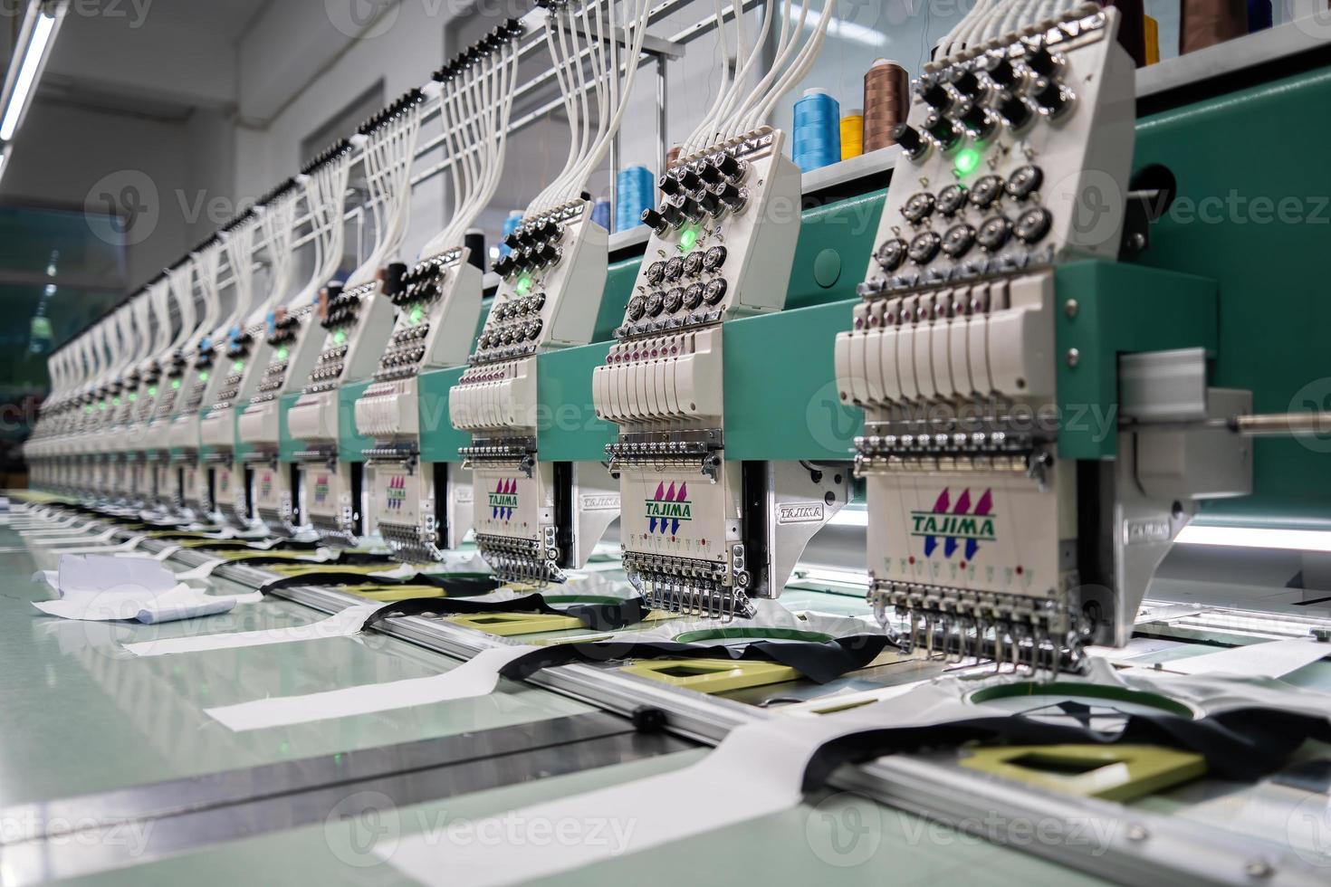 Modern and automatic high technology sewing machine for textile or clothing apparel making manufacturing process in industrial. Digital textile industry. Computerized embroidery. photo