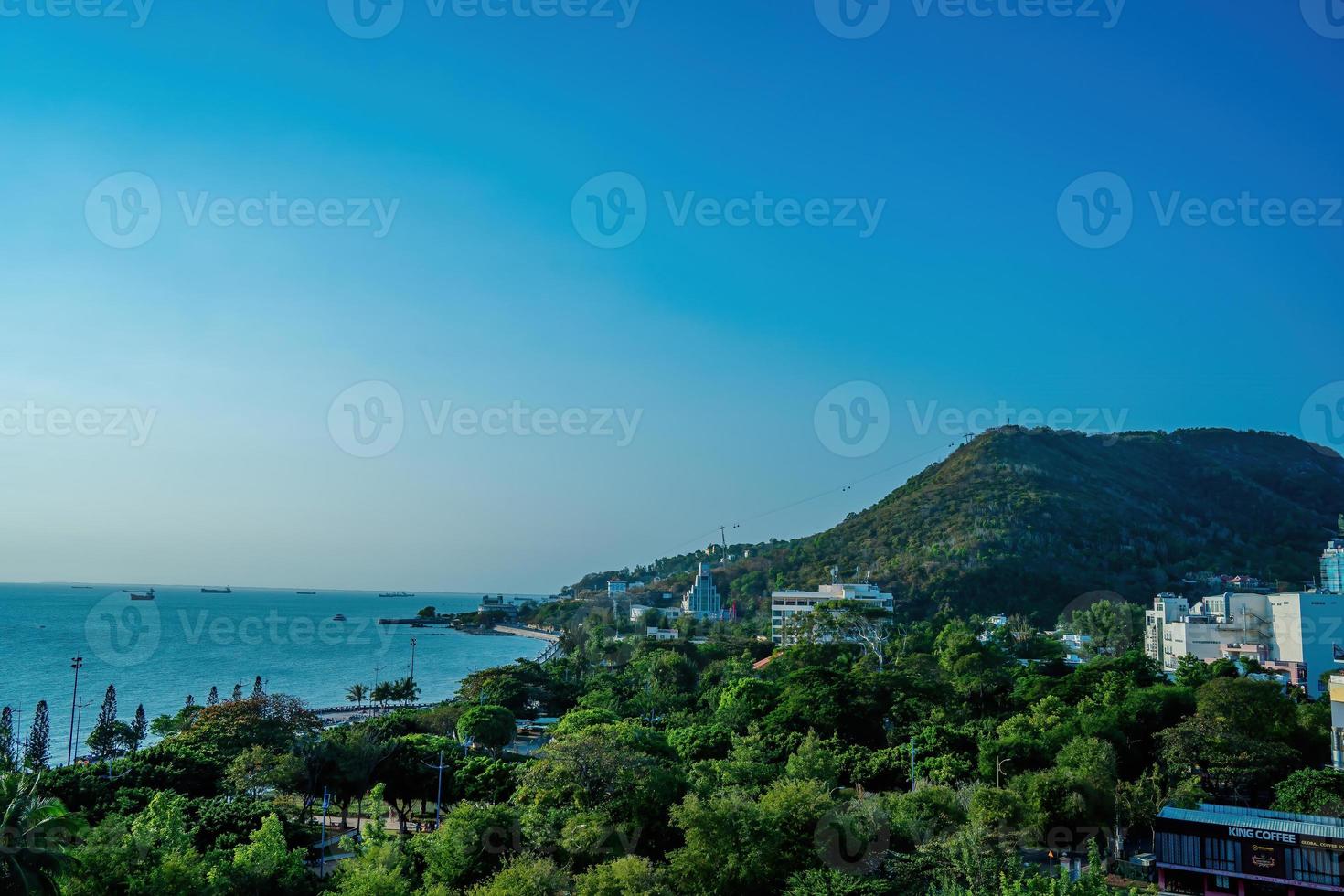 vista aérea de la ciudad de vung tau con hermosa puesta de sol y tantos barcos. vista panorámica costera de vung tau desde arriba, con olas, costa, calles, cocoteros y montaña tao phung en vietnam. foto