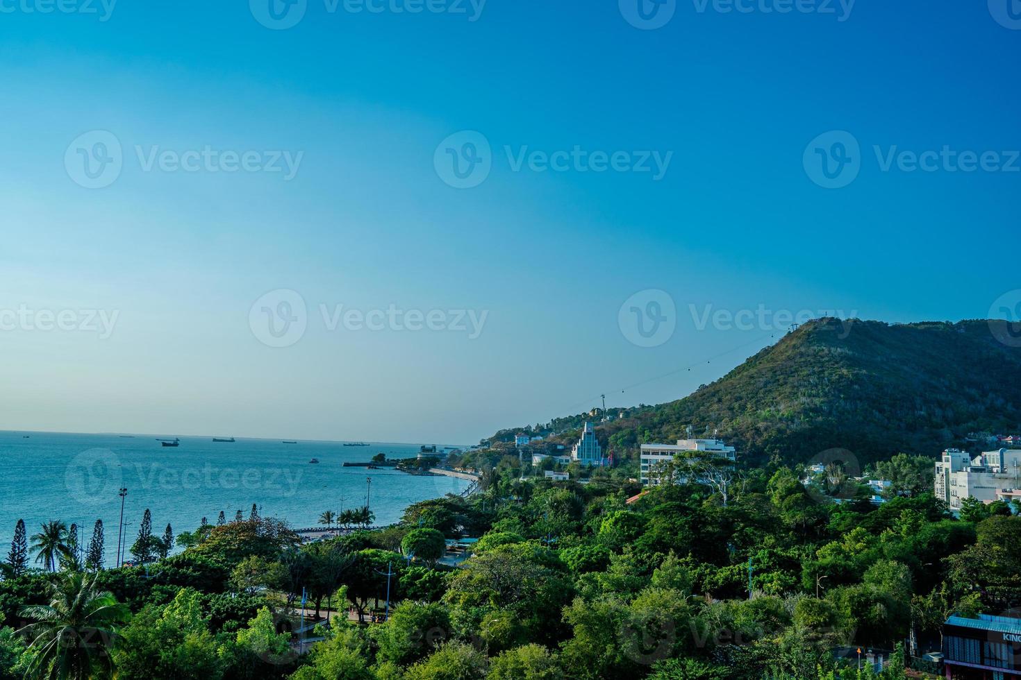 Vung Tau city aerial view with beautiful sunset and so many boats. Panoramic coastal Vung Tau view from above, with waves, coastline, streets, coconut trees and Tao Phung mountain in Vietnam. photo