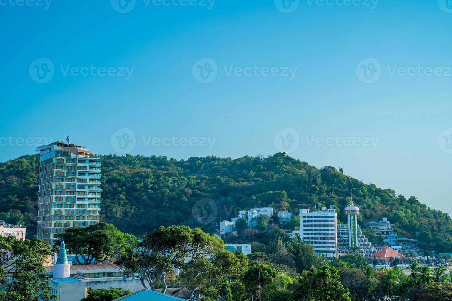 Vung Tau city aerial view with beautiful sunset and so many boats. Panoramic coastal Vung Tau view from above, with waves, coastline, streets, coconut trees and Tao Phung mountain in Vietnam. photo