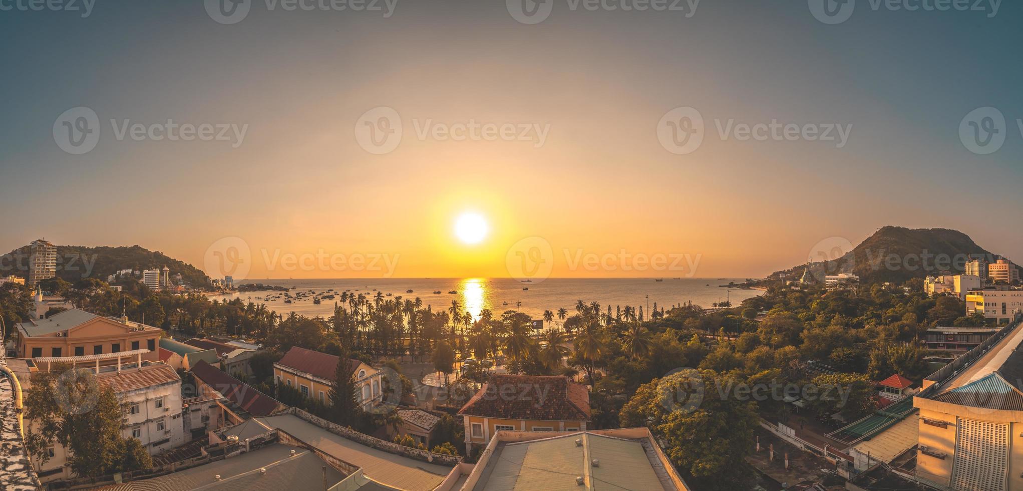 Vung Tau city aerial view with beautiful sunset and so many boats. Panoramic coastal Vung Tau view from above, with waves, coastline, streets, coconut trees and Tao Phung mountain in Vietnam. photo