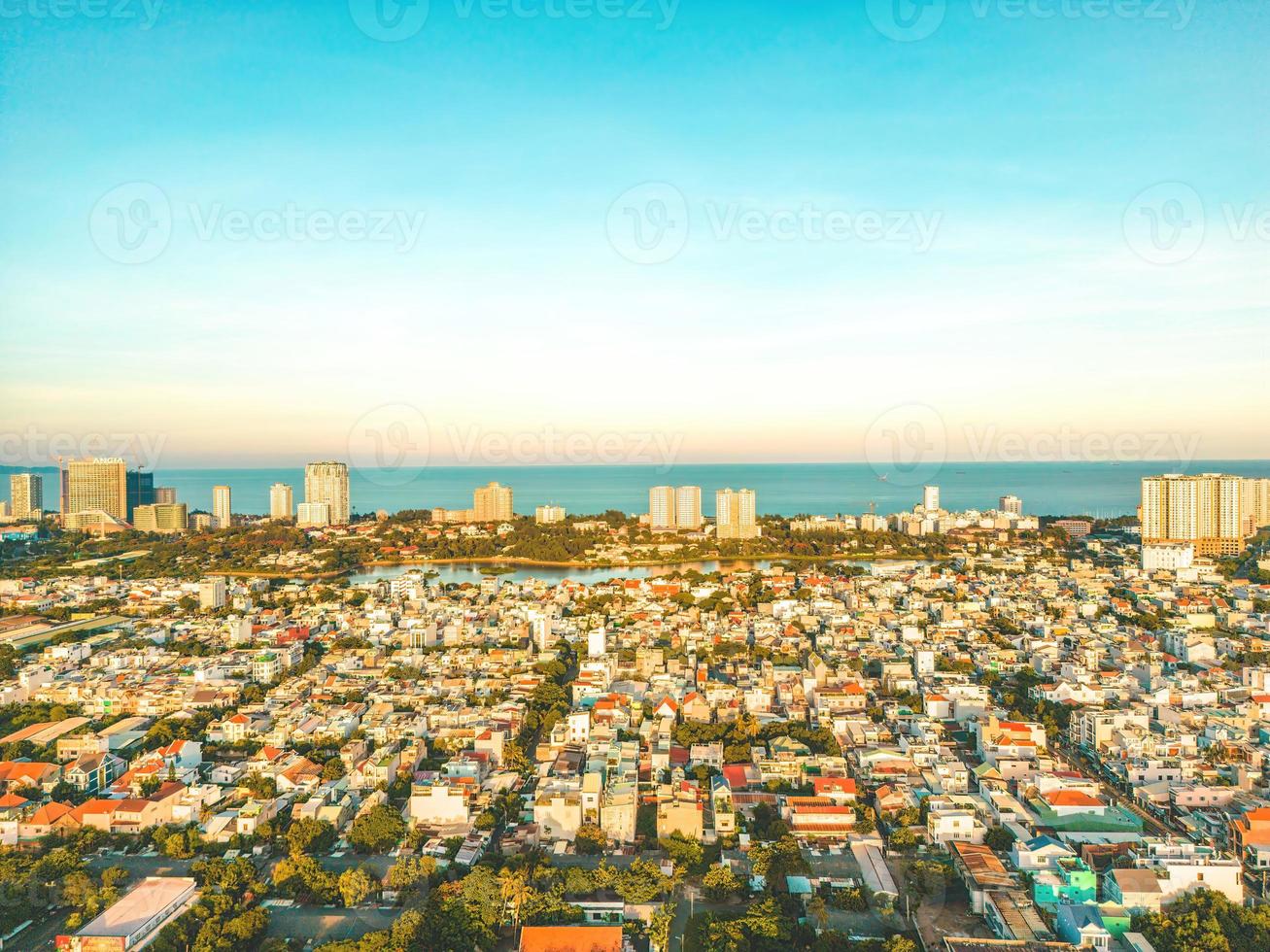Vung Tau city aerial view with beautiful sunset and so many boats. Panoramic coastal Vung Tau view from above, with waves, coastline, streets, coconut trees and Tao Phung mountain in Vietnam. photo