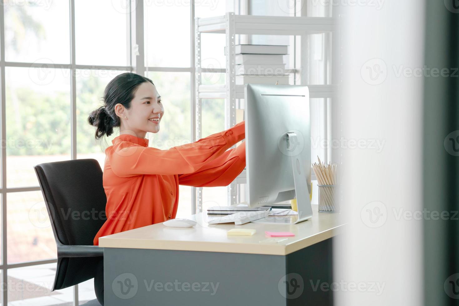 Businesswoman in office working hard. She is sticking paper reminders on computer monitor photo