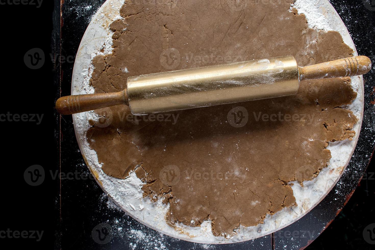 gingerbread dough on round marble with gold rolling pin top view photo