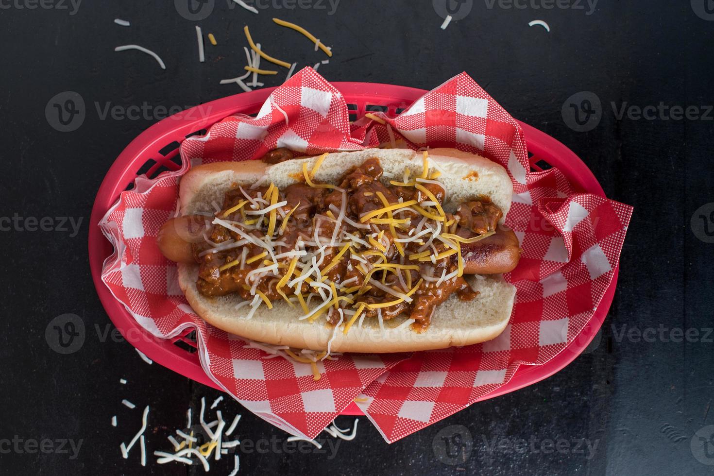 chilli dog with onions and cheese on a bun flat lay photo