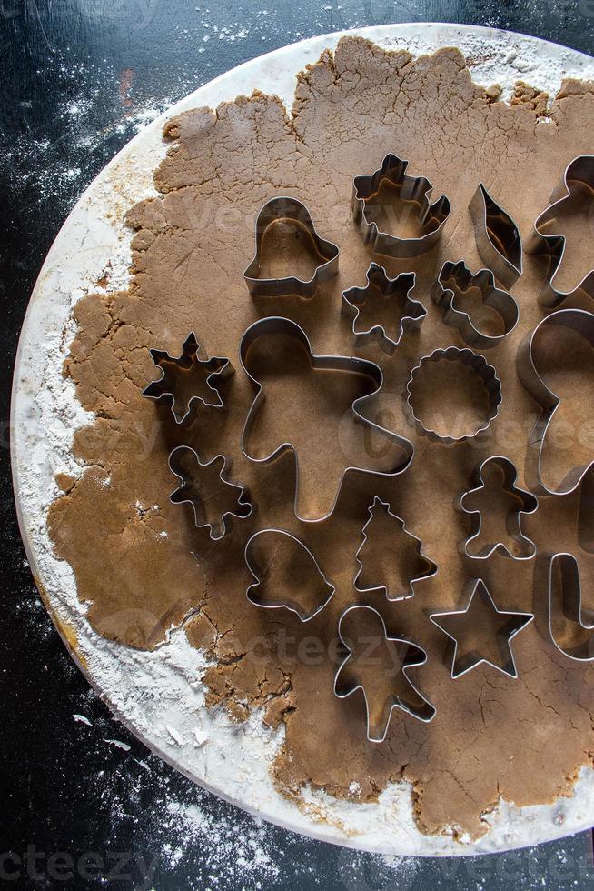 Christmas cookie cutters on gingerbread dough flat lay photo