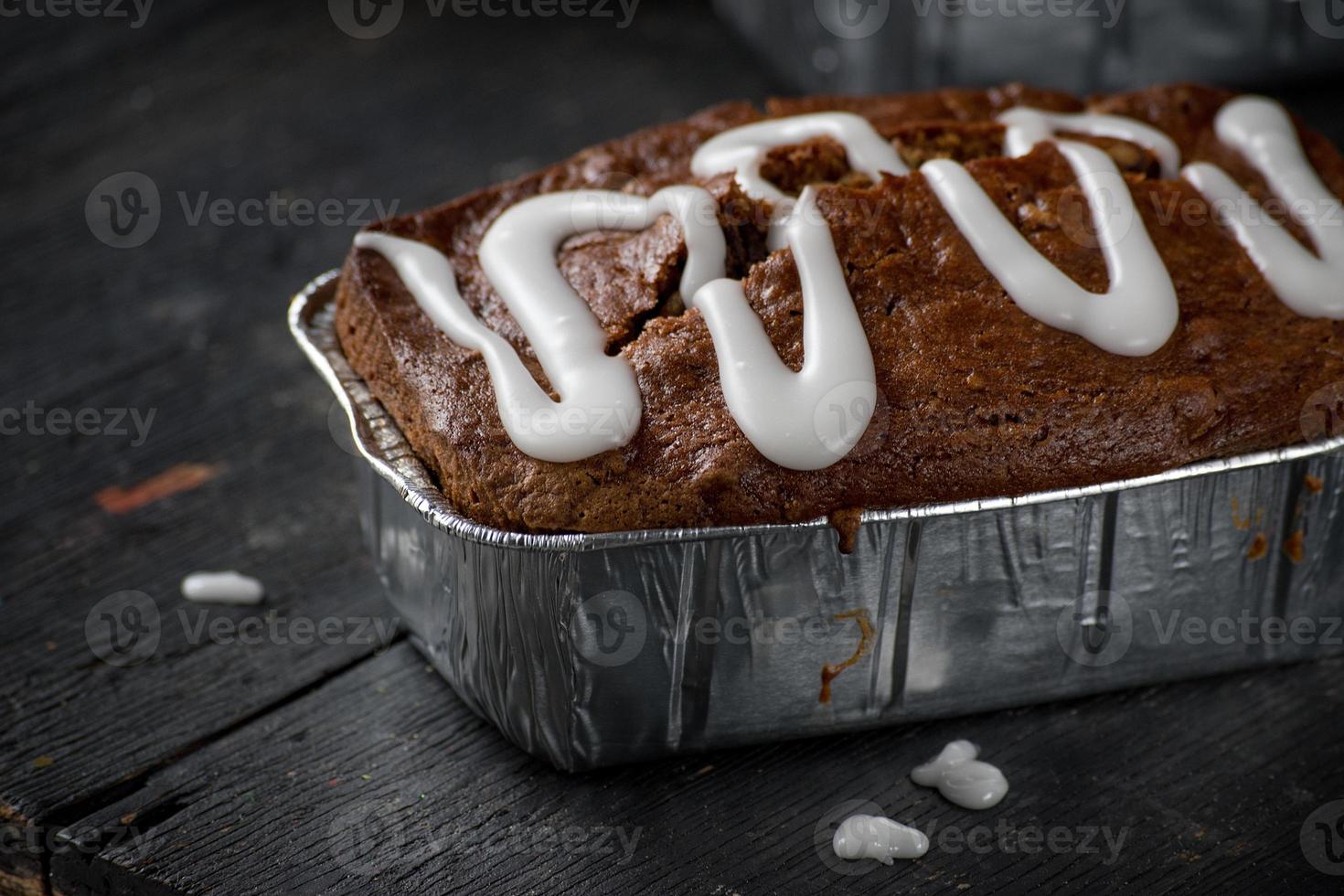 pumpkin pecan bread loaf with sugar glaze drizzle on dark wood table photo