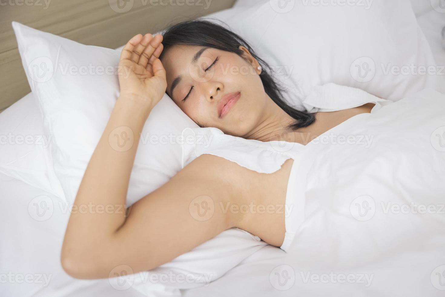 Young asian woman sleeping in bed at bedroom. she is lying on side and relax with eyes closed photo