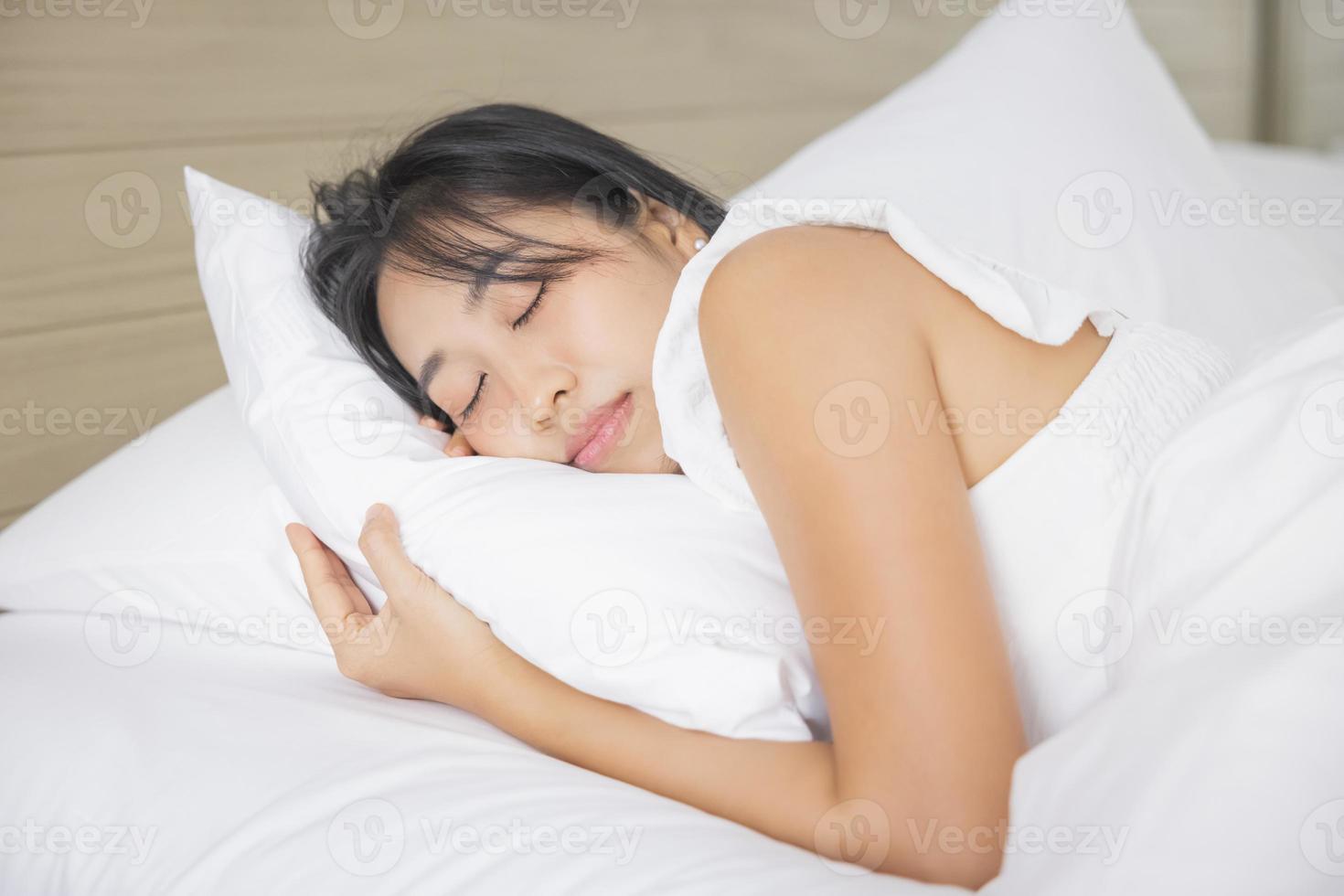 Young asian woman sleeping in bed at bedroom. she is lying on side and relax with eyes closed photo