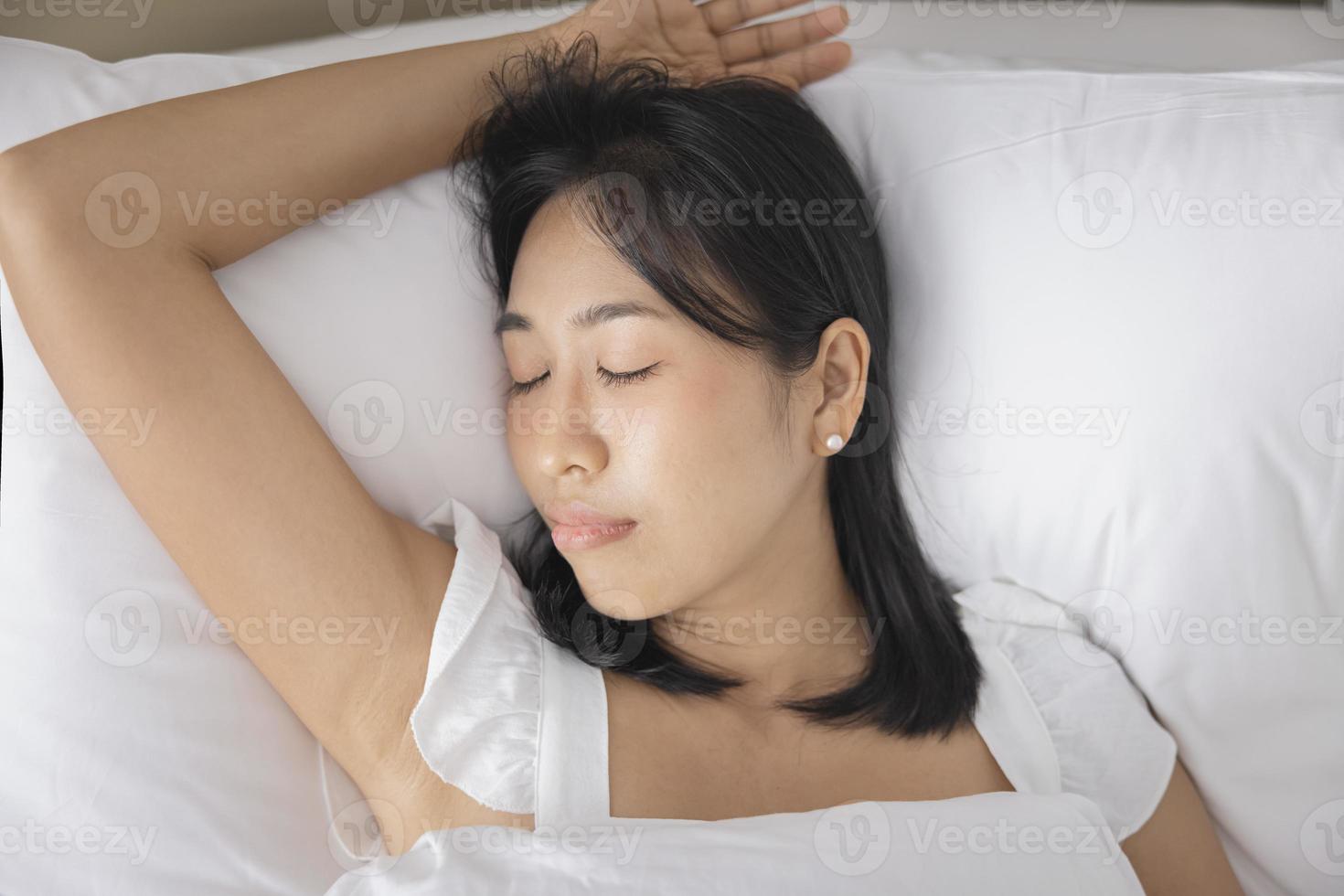 Young Asian woman sleeping in her bed and relaxing in bedroom. they are lying on the side and relax with their eyes closed photo