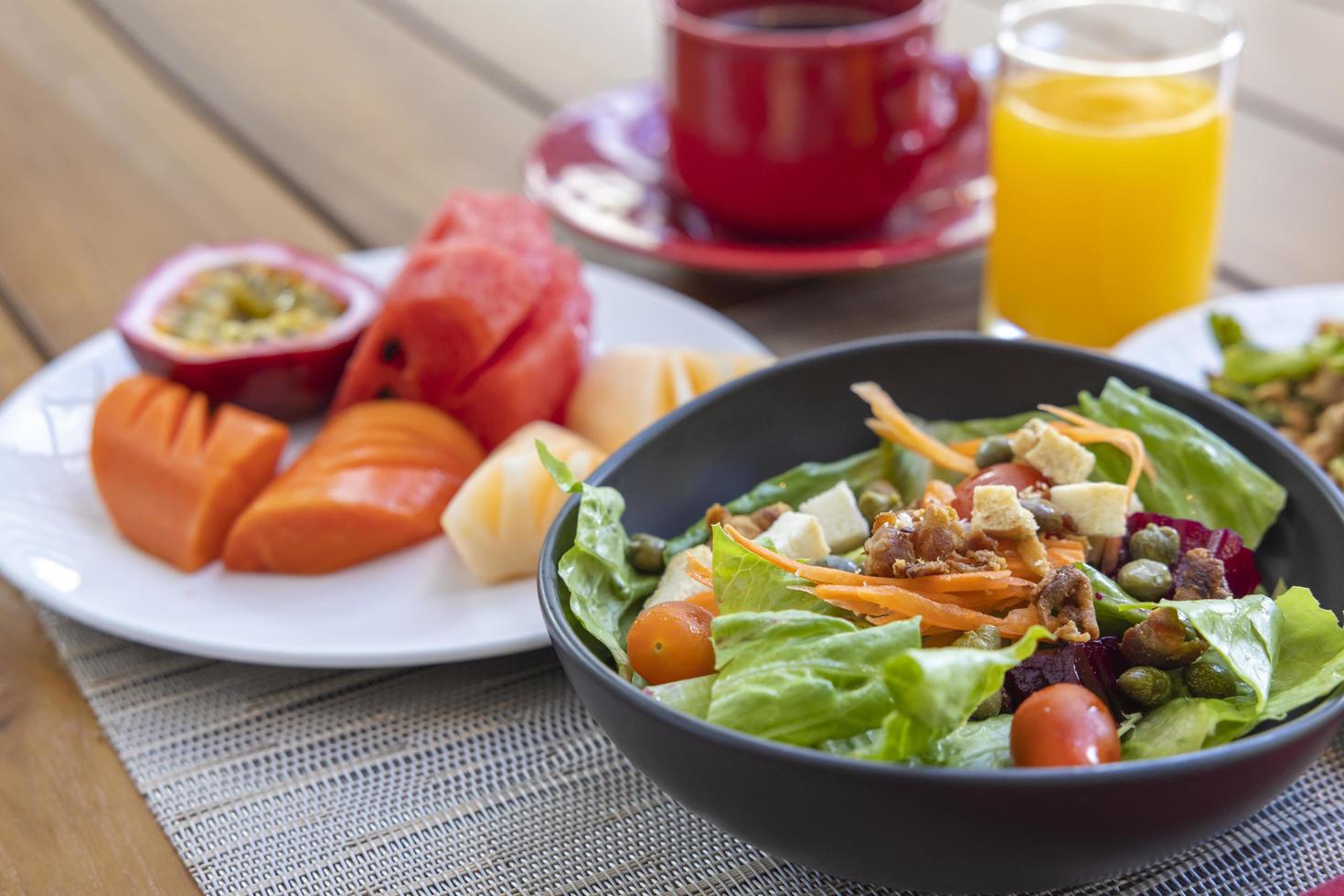 Breakfast. Vegetable salad, fruits such as watermelon, papaya, melon, passion fruit, orange juice and coffee. placed on a gray placemat. photo