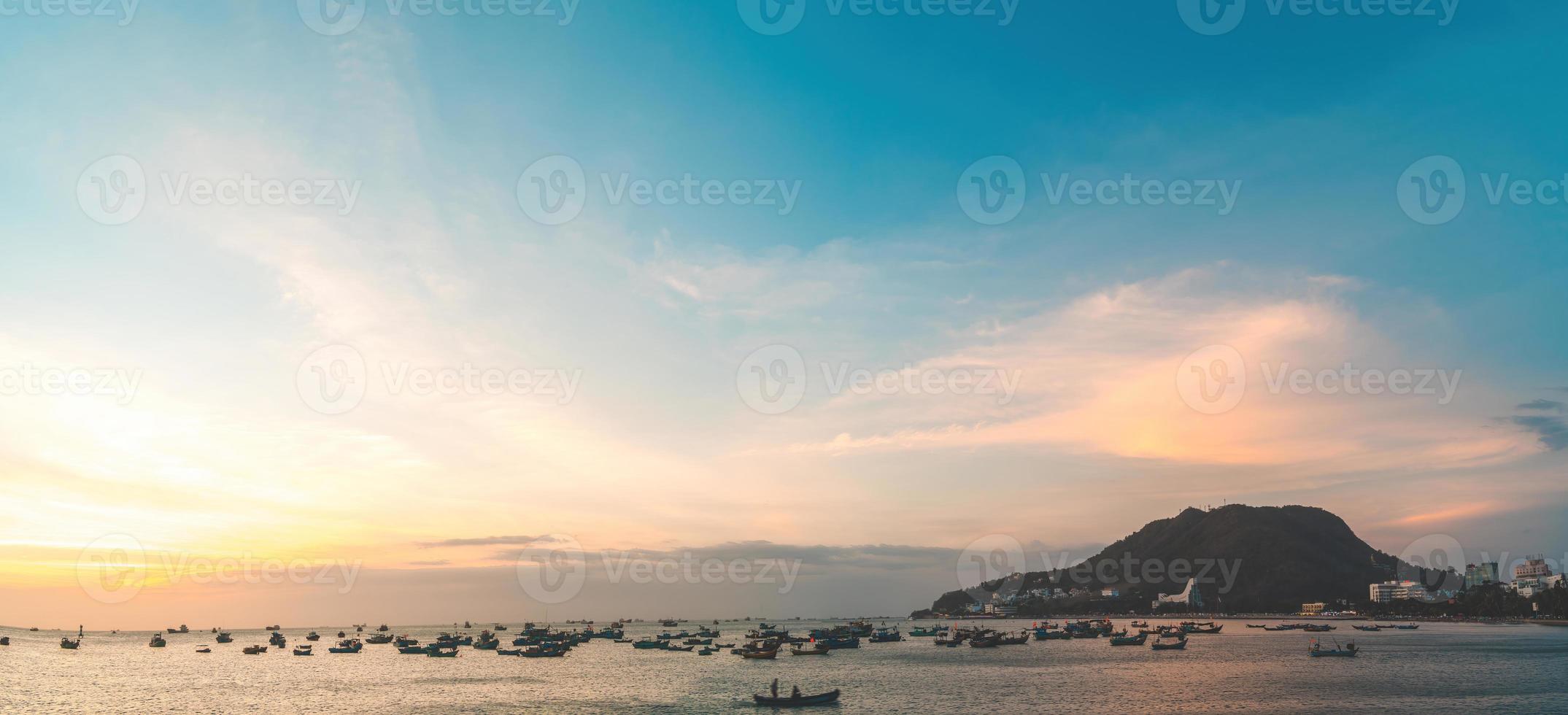 Vung Tau city aerial view with beautiful sunset and so many boats. Panoramic coastal Vung Tau view from above, with waves, coastline, streets, coconut trees and Tao Phung mountain in Vietnam. photo