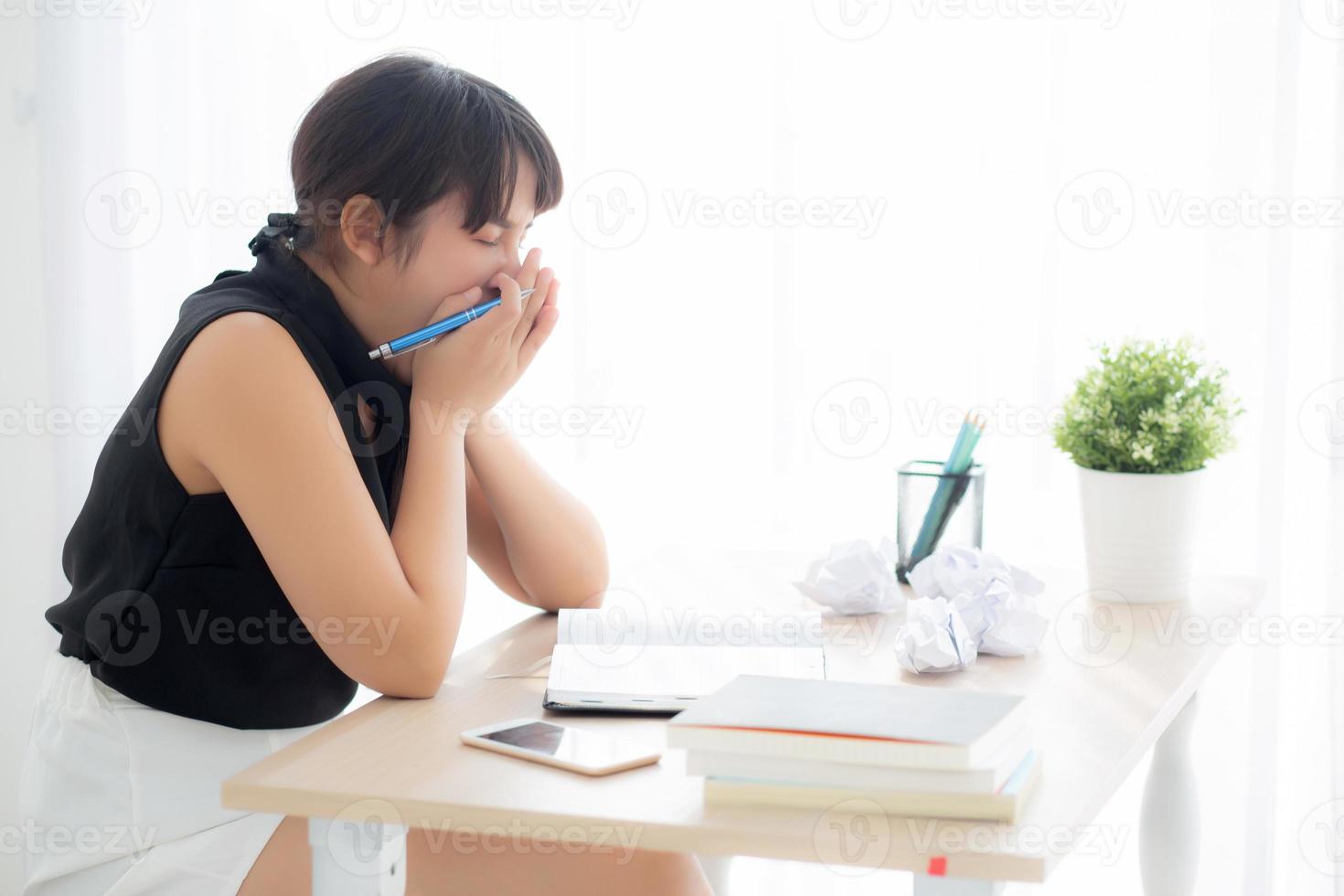 Beautiful asian woman tired and stressed with writing overworked at desk, girl with worried not idea with notebook and crumpled paper at office, freelance and business concept. photo