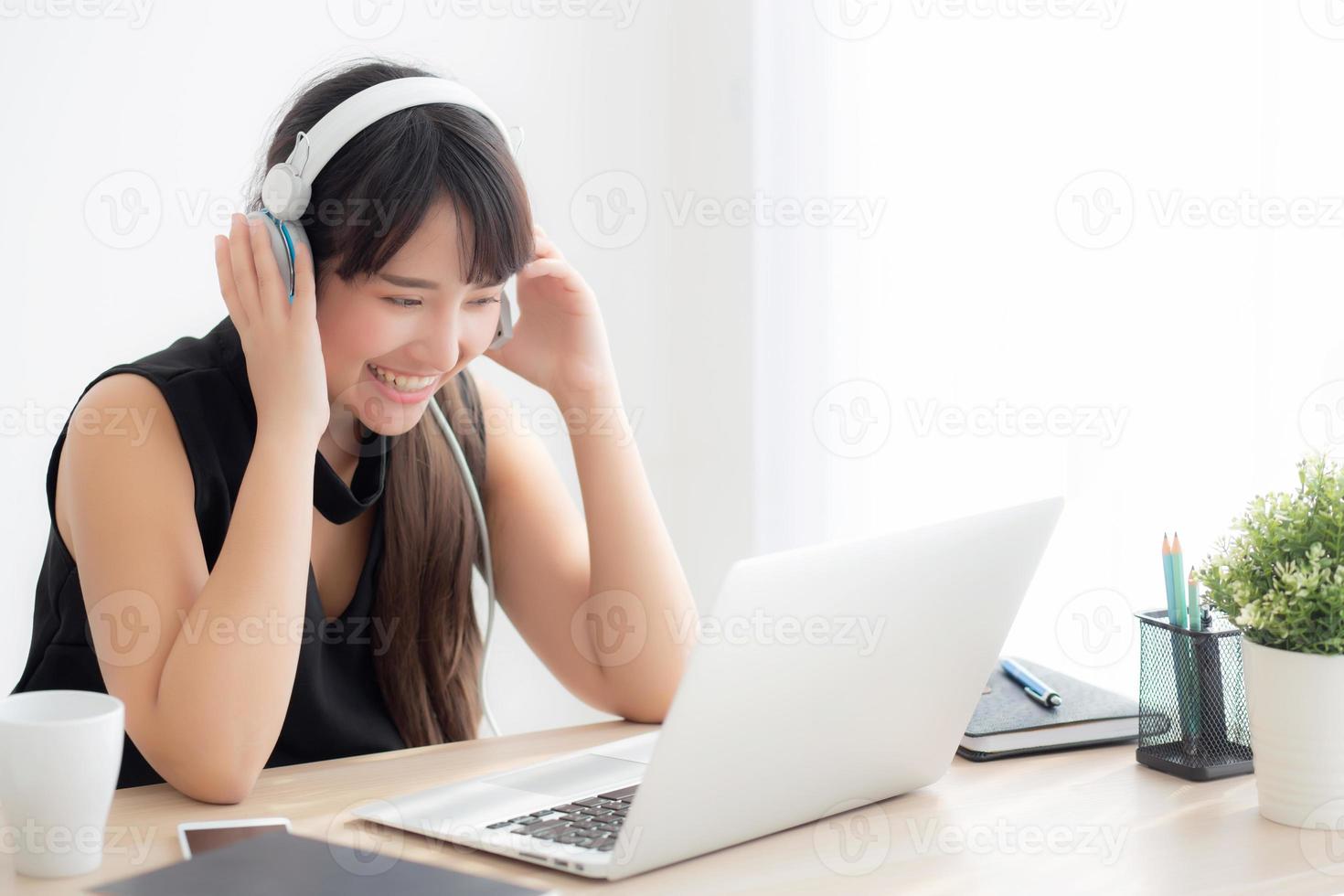 Beautiful young asian woman wear headphone smiling say hello using chat video call on laptop computer, girl relax enjoy listening music online, education learning, communication and lifestyle concept. photo