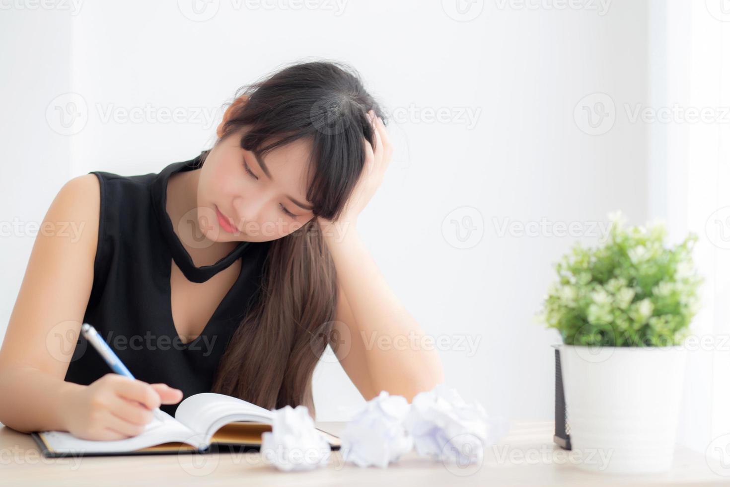 Beautiful asian woman tired and stressed with writing overworked at desk, girl with worried not idea with notebook and crumpled paper at office, freelance and business concept. photo