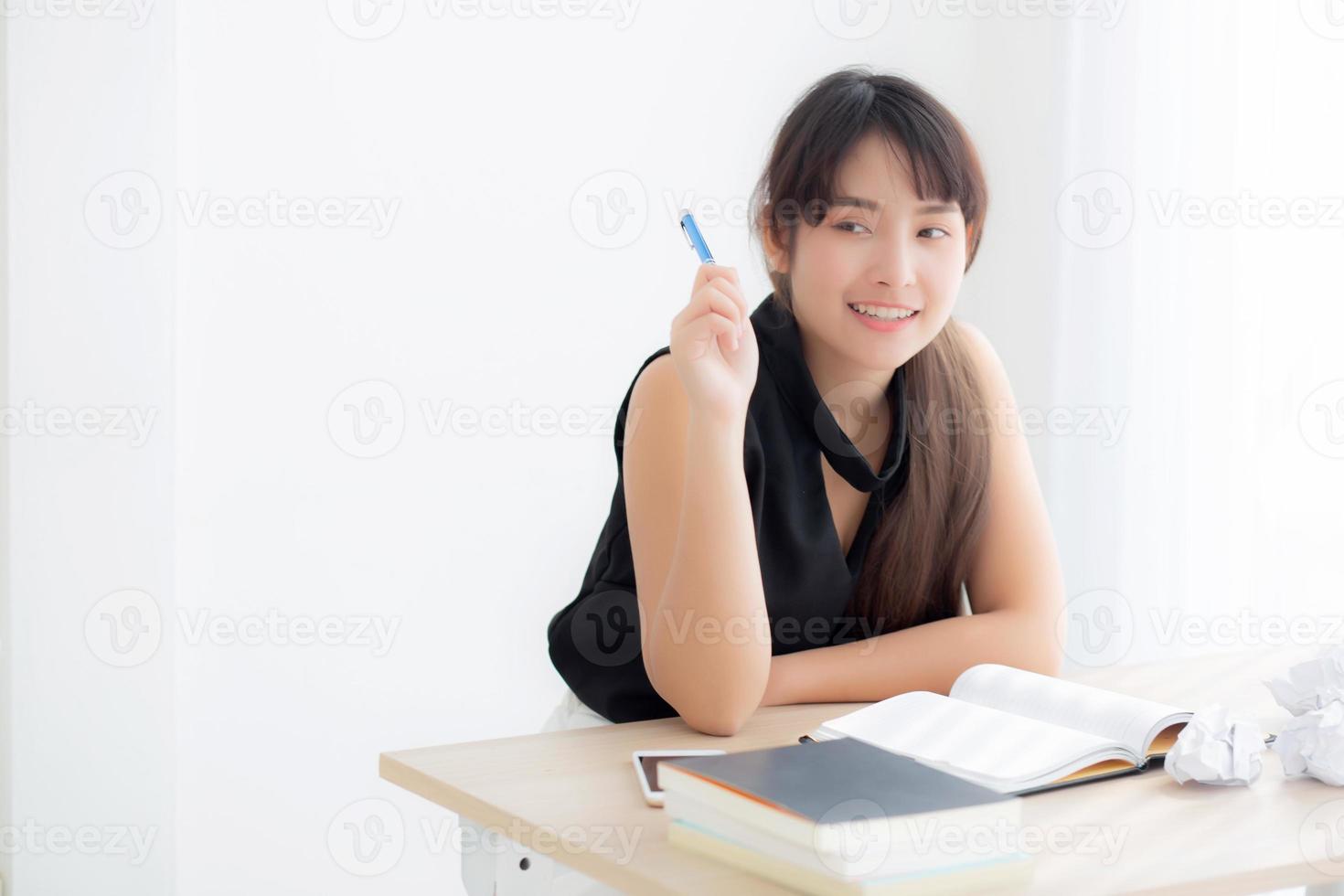 Beautiful asian woman writer smiling thinking idea writing on notebook diary with planning working on desk office, lifestyle asia girl have inspiration with success, education and business concept. photo