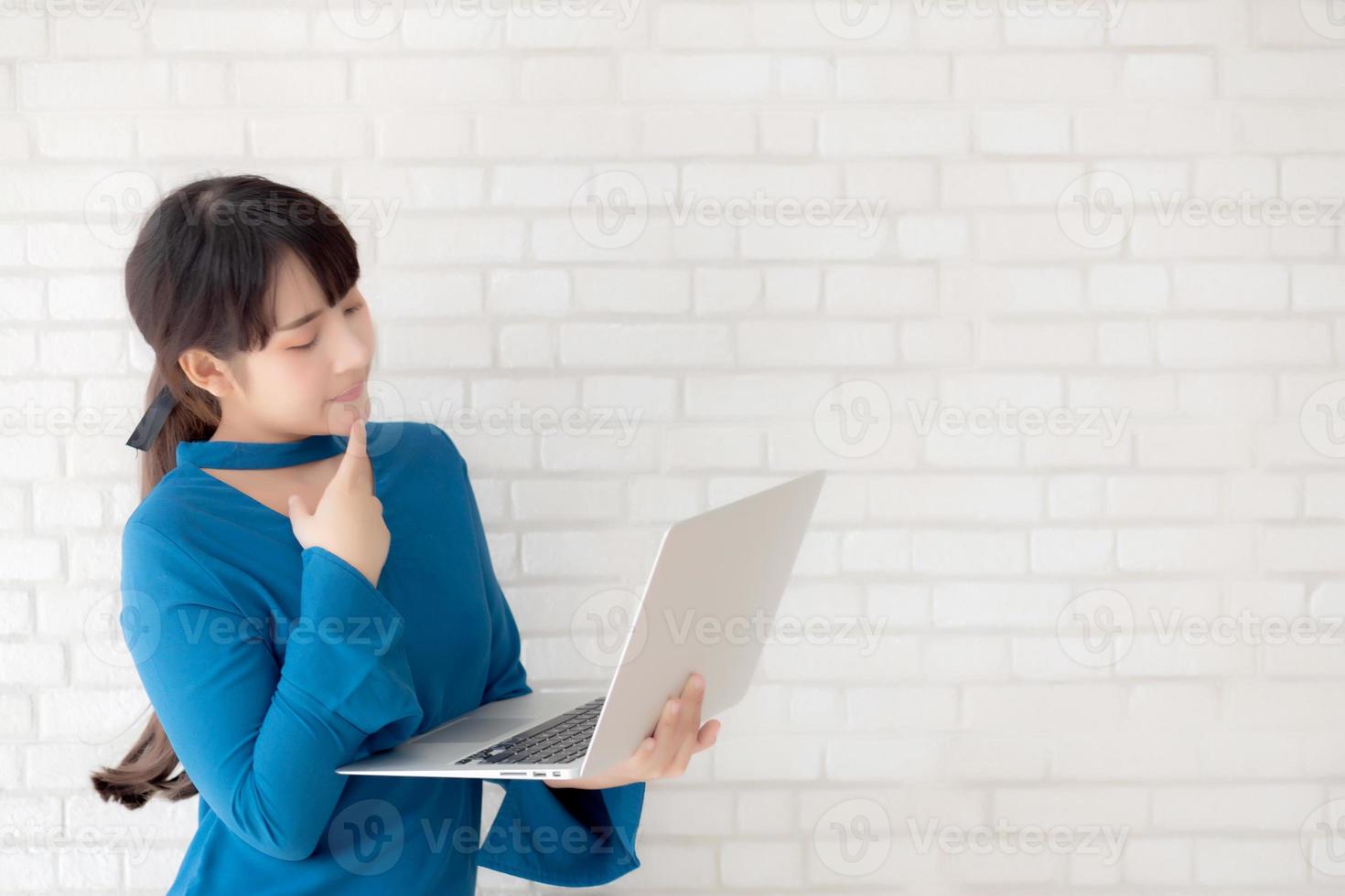 Beautiful asian young woman hipster using working laptop thinking idea on cement concrete background, girl doubt and question with computer internet online, freelance and business concept. photo