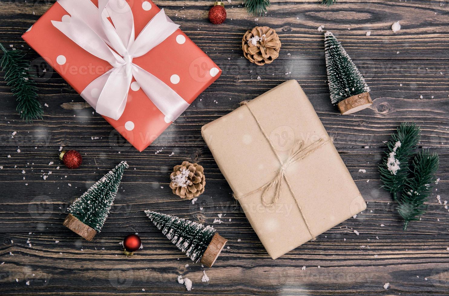 composición navideña con caja de regalo roja y decoración de etiquetas sobre fondo de madera, año nuevo y navidad o aniversario con regalos sobre mesa de madera en temporada, vista superior o puesta plana. foto