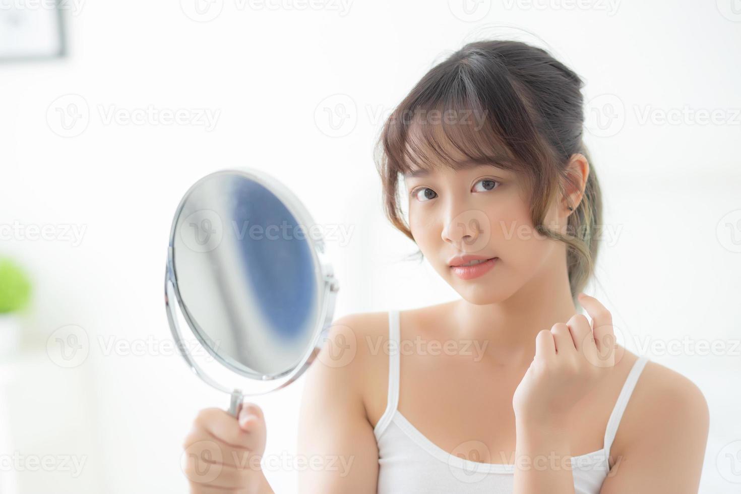 Beautiful face young asian woman with happy smiling and looking mirror, makeup of beauty facial girl with skincare and cosmetic treatment, refresh of female and clean for charming, healthy concept. photo