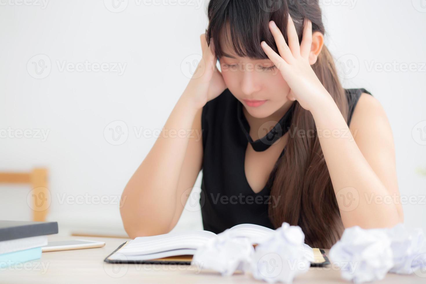 Beautiful asian woman tired and stressed with writing overworked at desk, girl with worried not idea with notebook and crumpled paper at office, freelance and business concept. photo
