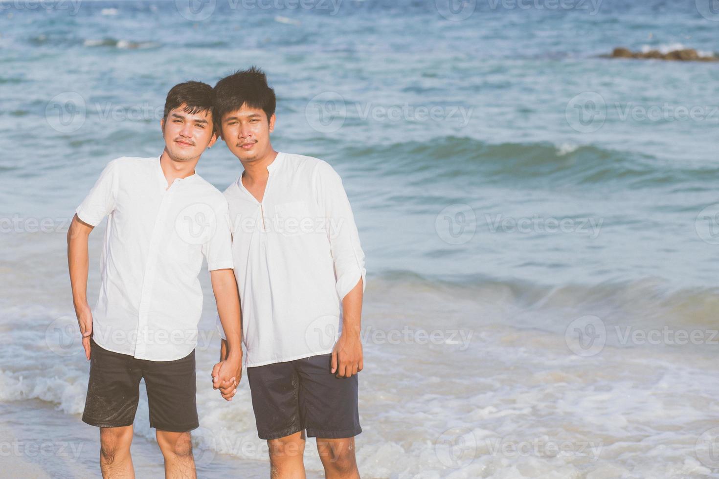 retrato homosexual joven pareja asiática de pie juntos en la playa en verano, asia gay tomados de la mano yendo al mar por placer y relajarse con romántico y feliz en vacaciones en el mar, lgbt con concepto legal. foto