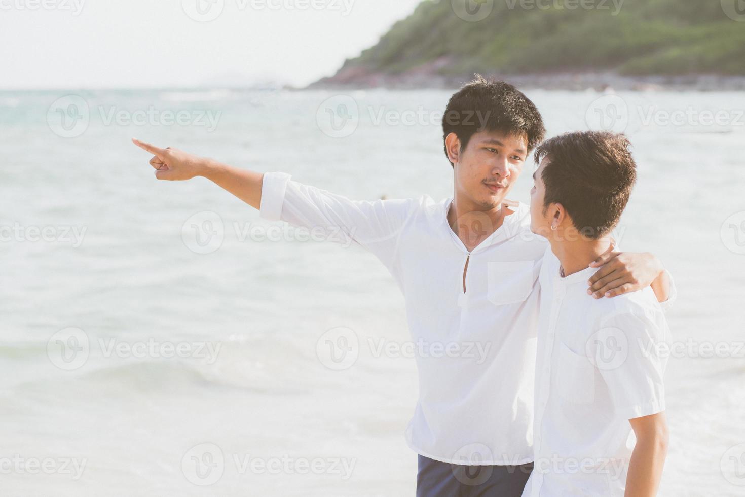 retrato homosexual joven pareja asiática de pie señalando algo juntos en la playa en verano, asia gay yendo al mar por placer con romántico y feliz en vacaciones en el mar, lgbt con concepto legal. foto