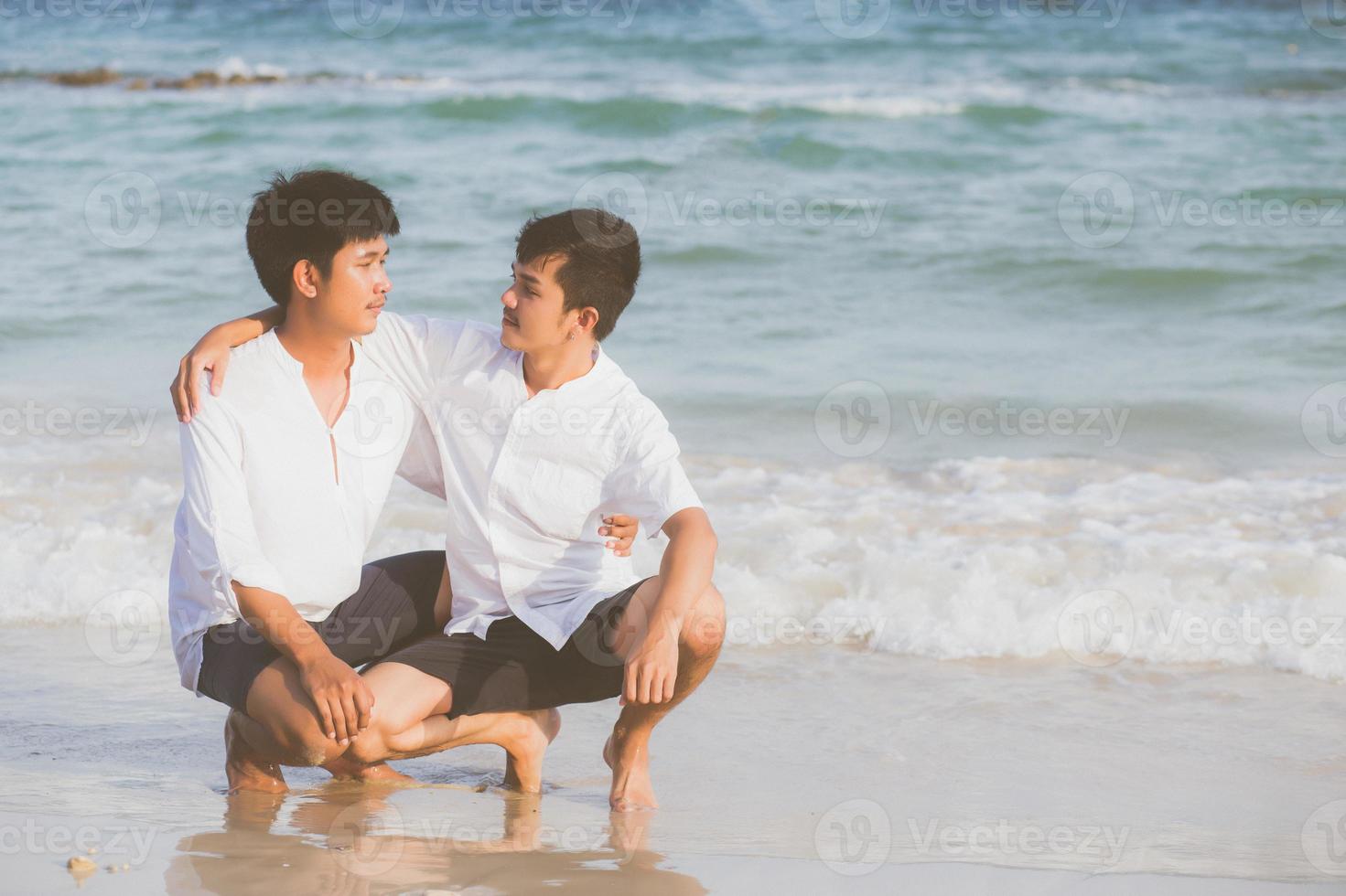 retrato homosexual joven pareja asiática sentada abrazada en la playa en verano, turismo gay de asia para el ocio y relajarse con romanticismo y felicidad en vacaciones en el mar, concepto legal lgbt. foto