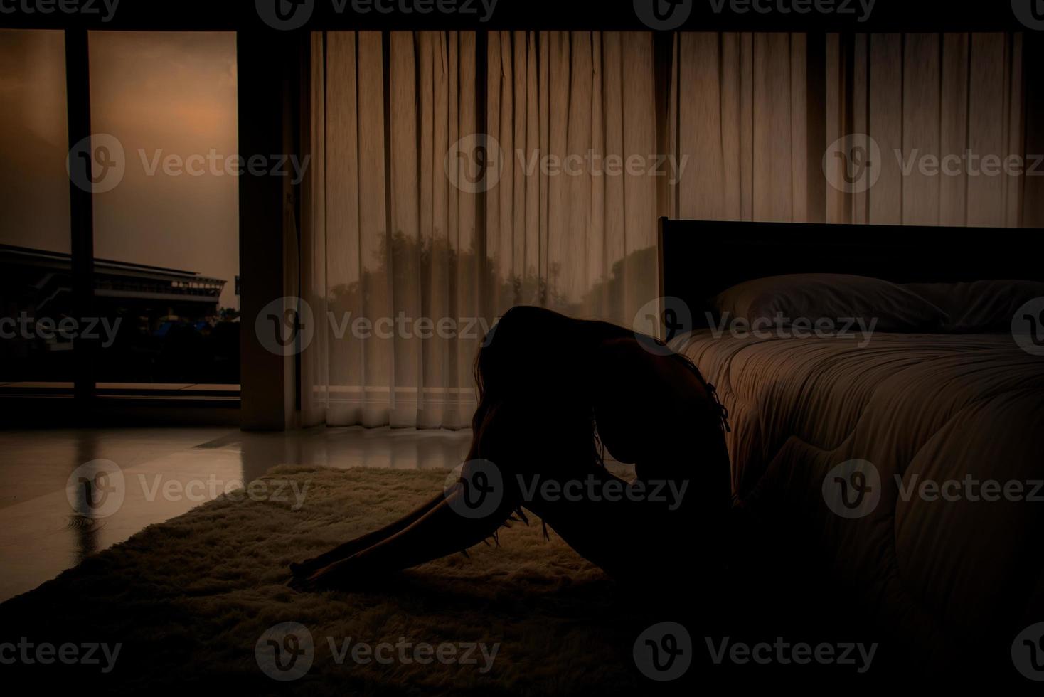 mujer joven sentada en el suelo en el dormitorio sintiéndose triste y deprimida por la noche. sufre de depresión, concepto de problema de salud mental. foto