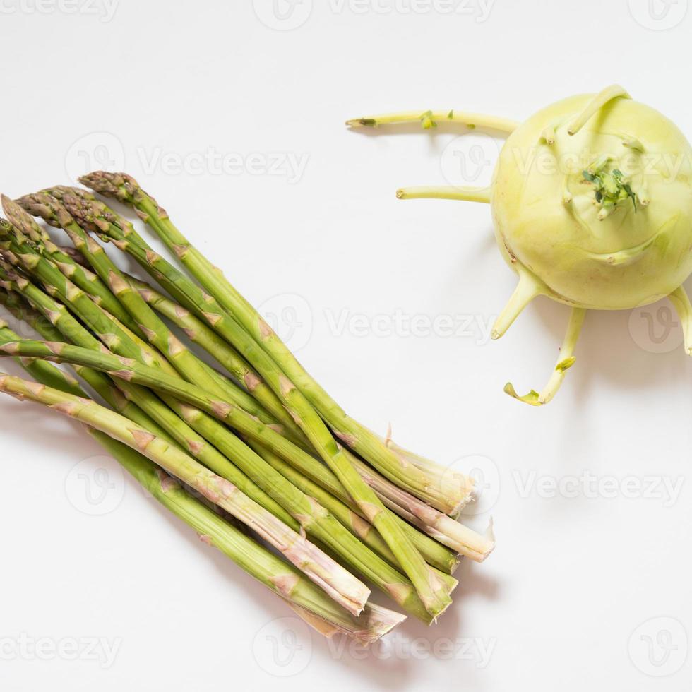 Kohlrabi, also known as german turnip, and a bunch of asparagus. White background, directly above photo