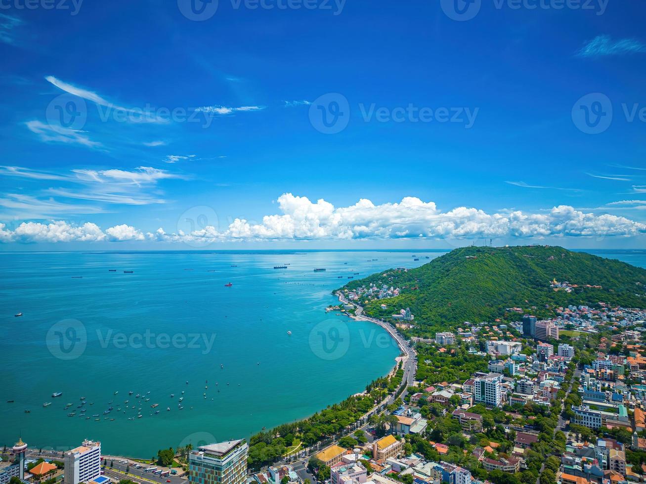 Vung Tau city aerial view with beautiful sunset and so many boats. Panoramic coastal Vung Tau view from above, with waves, coastline, streets, coconut trees and Tao Phung mountain in Vietnam. photo