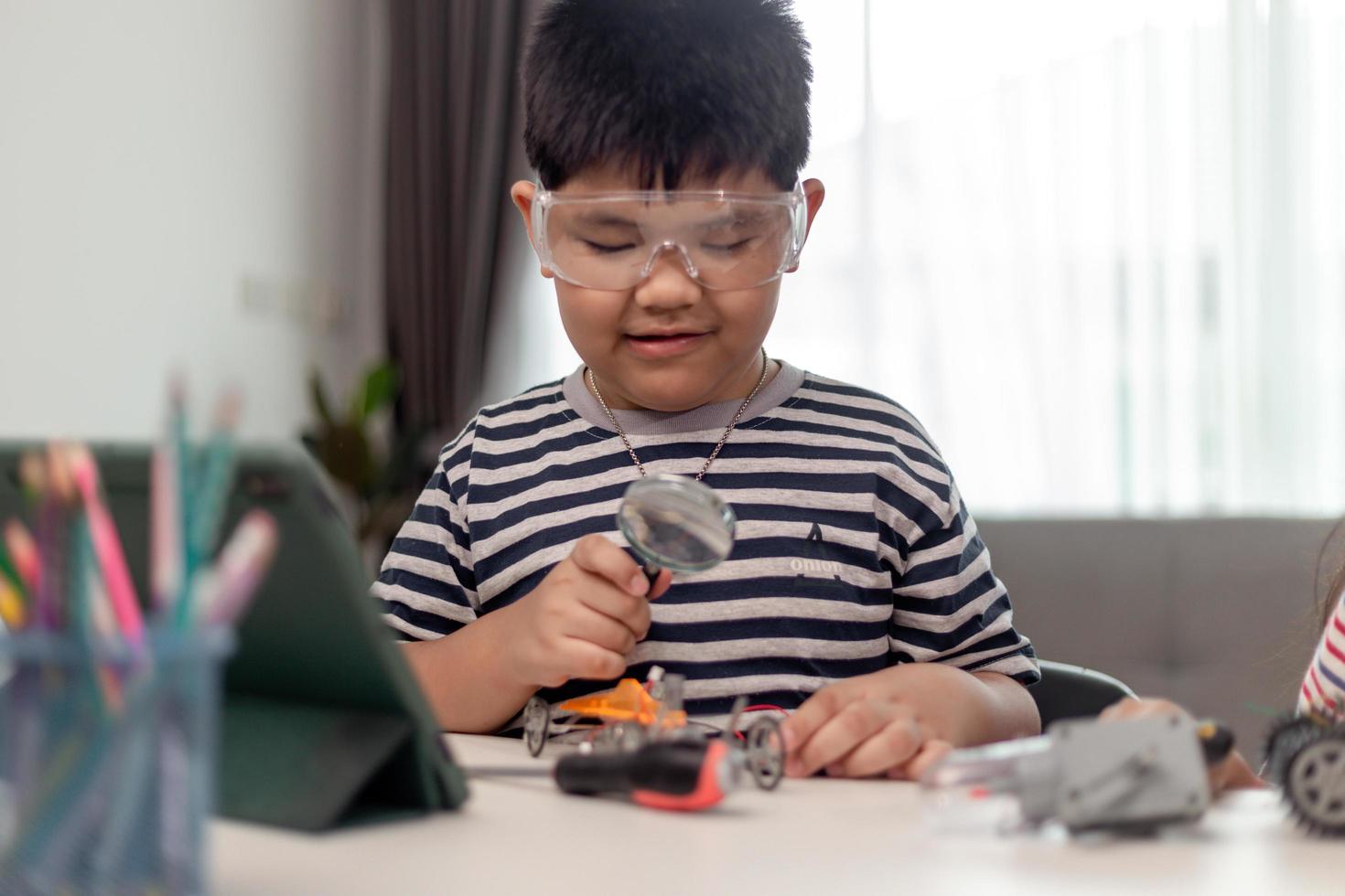 Young asia student remotely learn online at home  in coding robot car and electronic board cable in STEM, STEAM, mathematics engineer science technology computer code in robotics for kids. photo